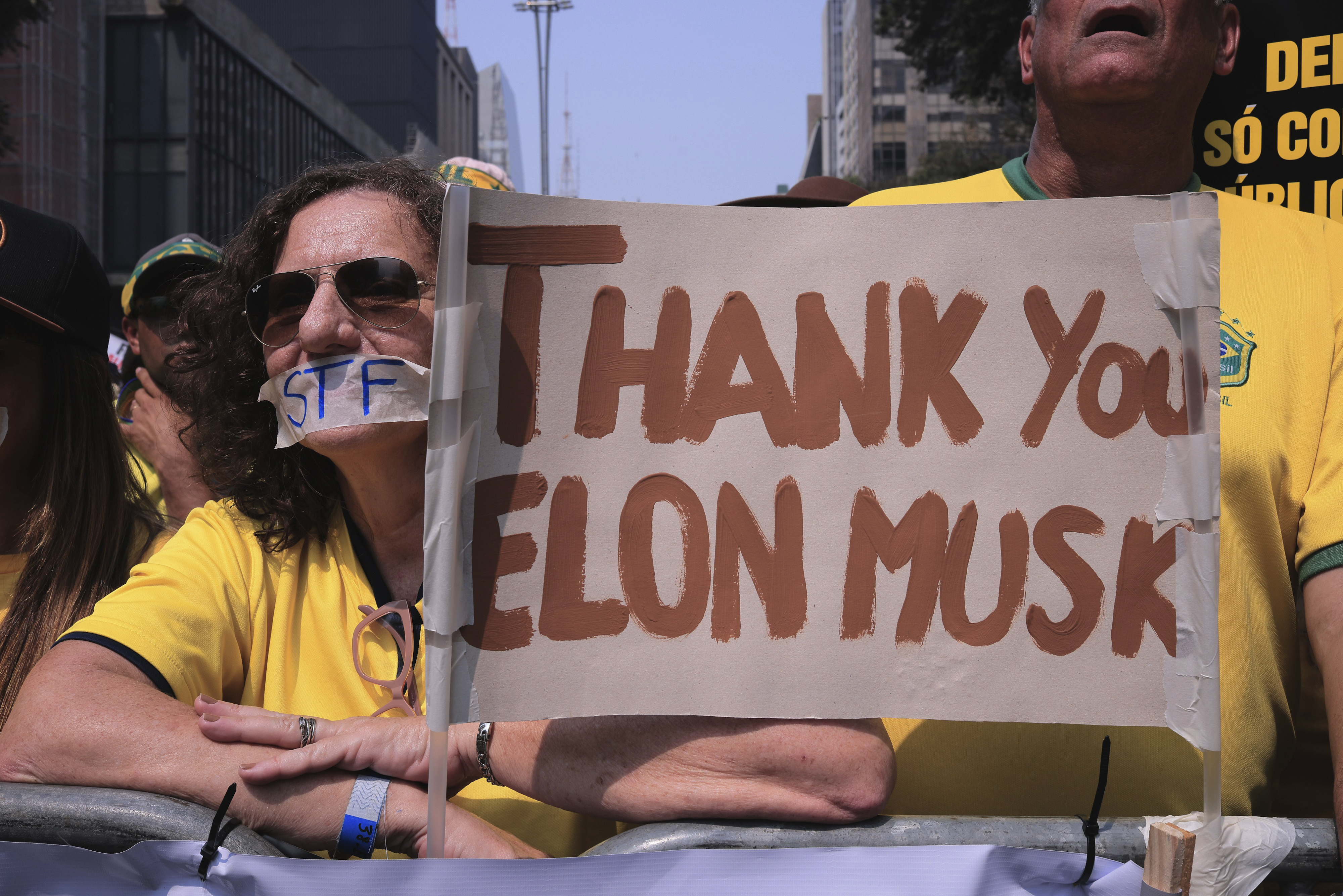 A protester holds up a hand-painted sign that reads, "Thank you Elon Musk."