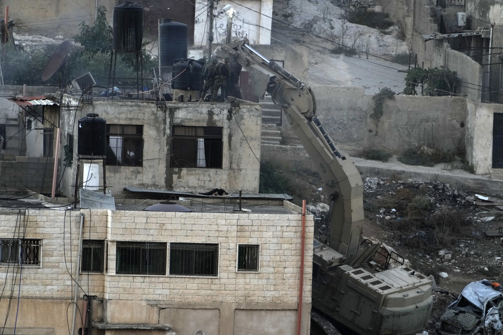 Israeli soldiers look over a rooftop where bodies lie motionless