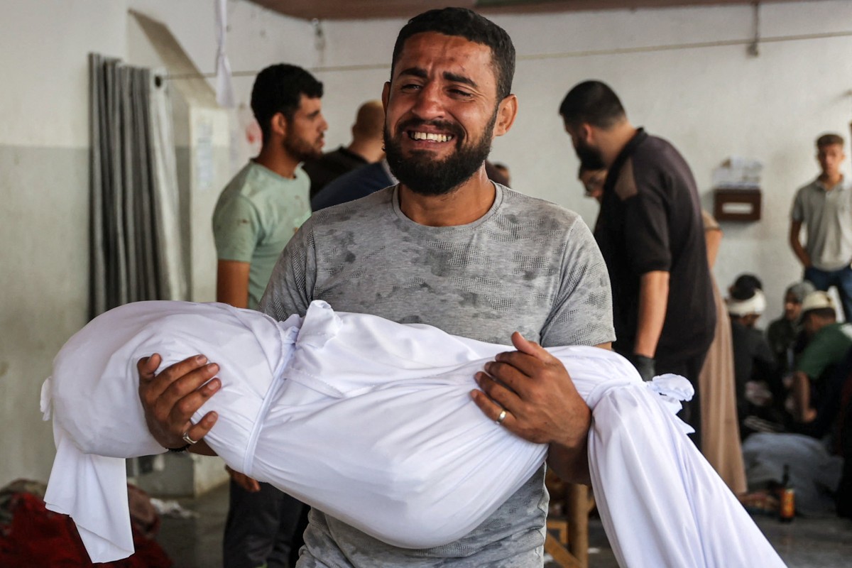 A man carries the shrouded body of a child