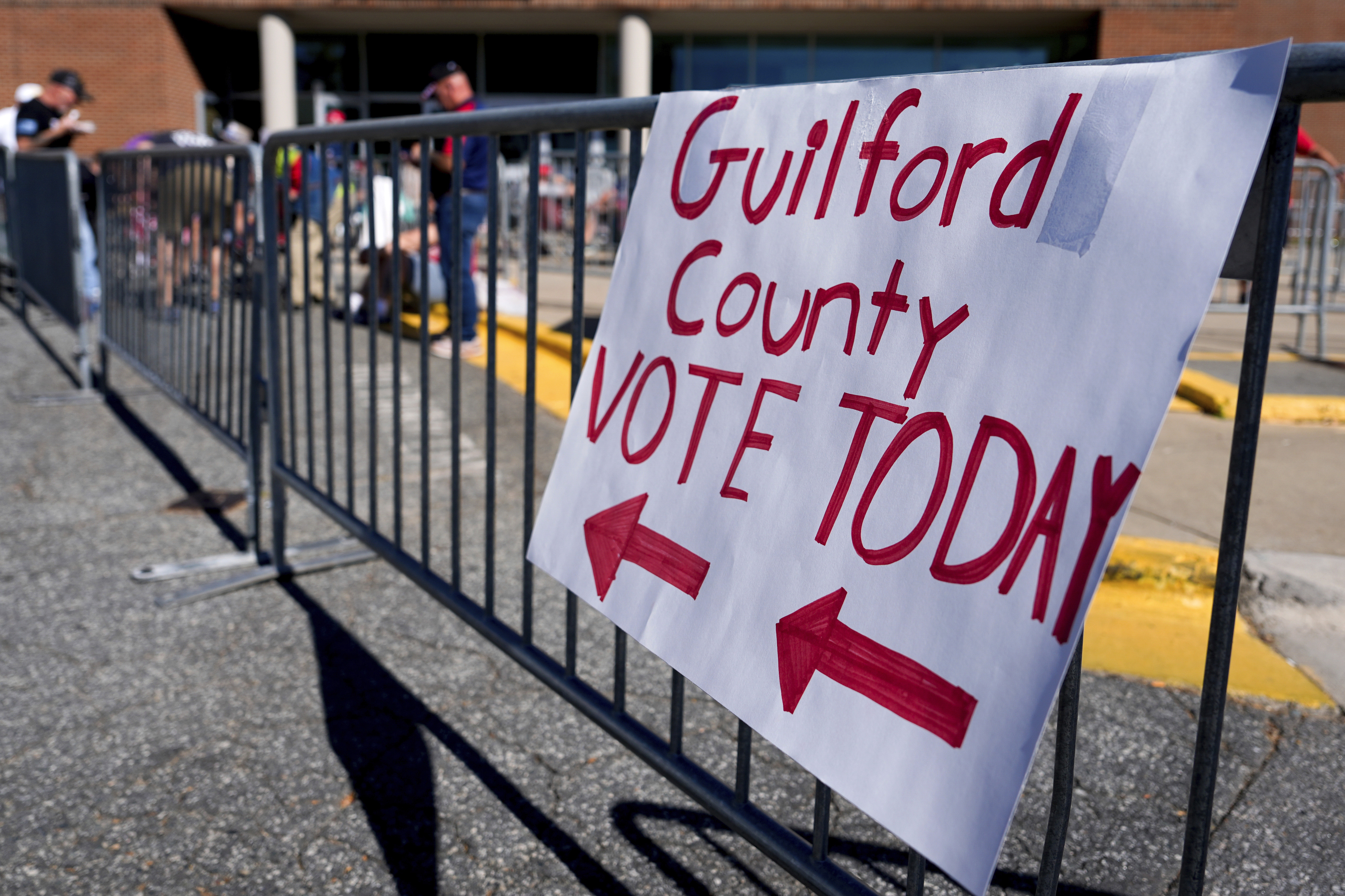 A sign on a metal barricade reads, "Guilford County Vote Today," with arrows pointing.