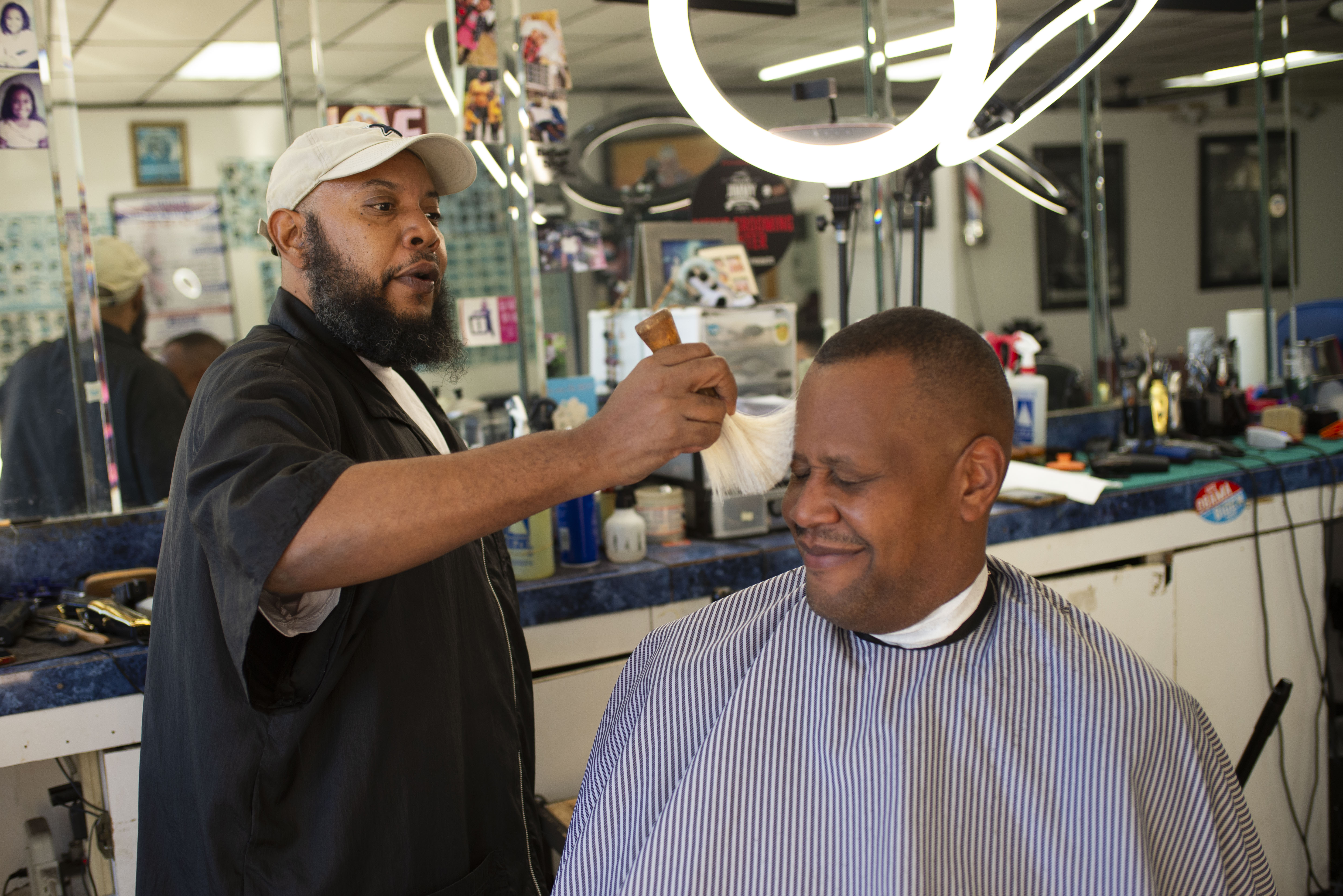 Barber Goody talks with customer Gardy Leandre in Austell, Georgia