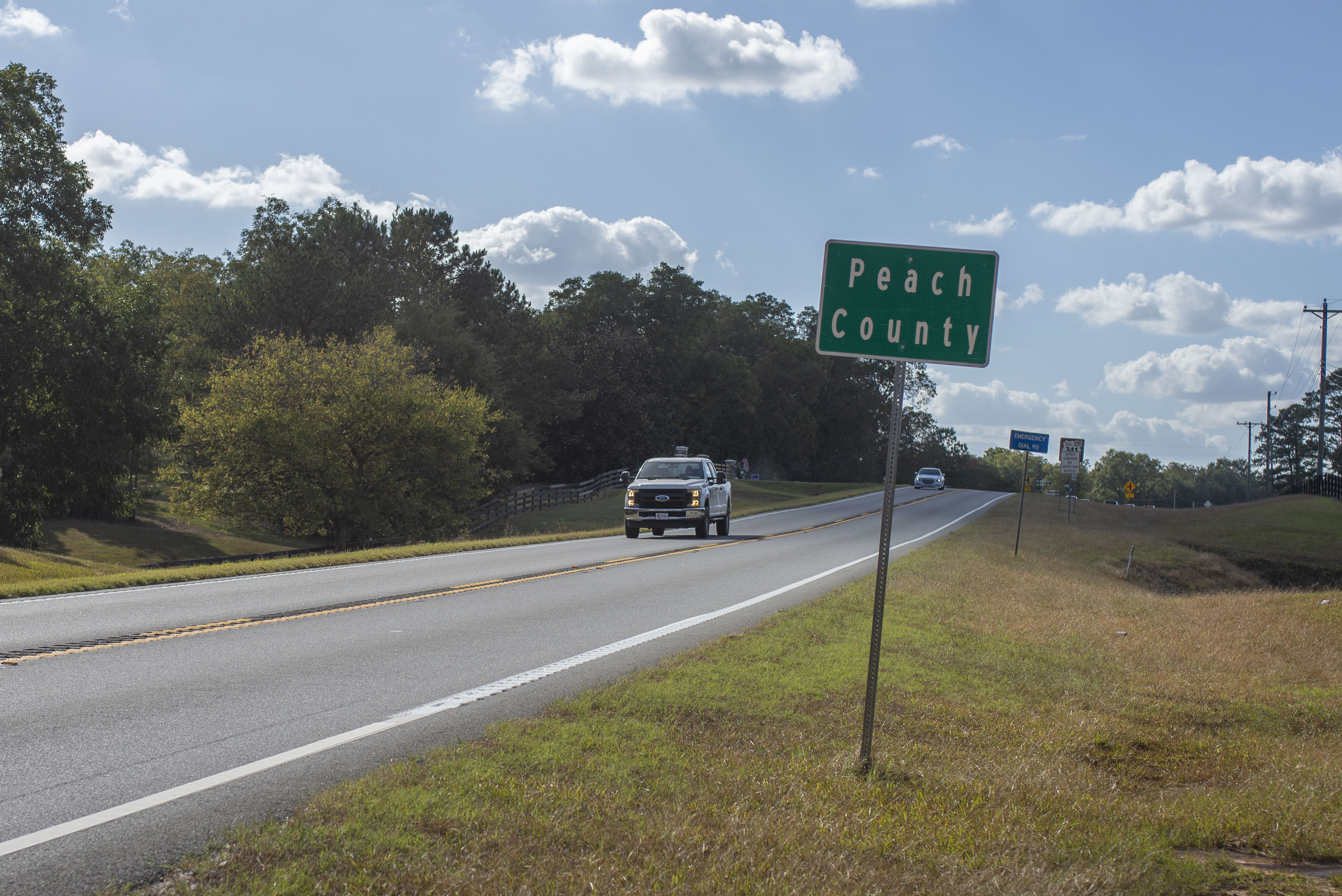 A sign labelled Peach County demarcates the county lines beside a roadway