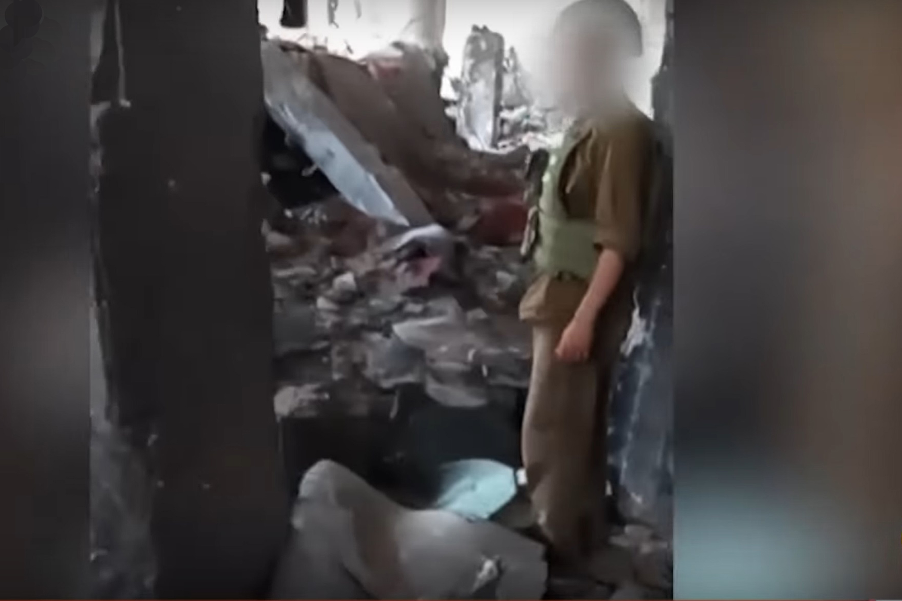 a screenshot of a video showing a man wearing a military uniform standing amid rubble