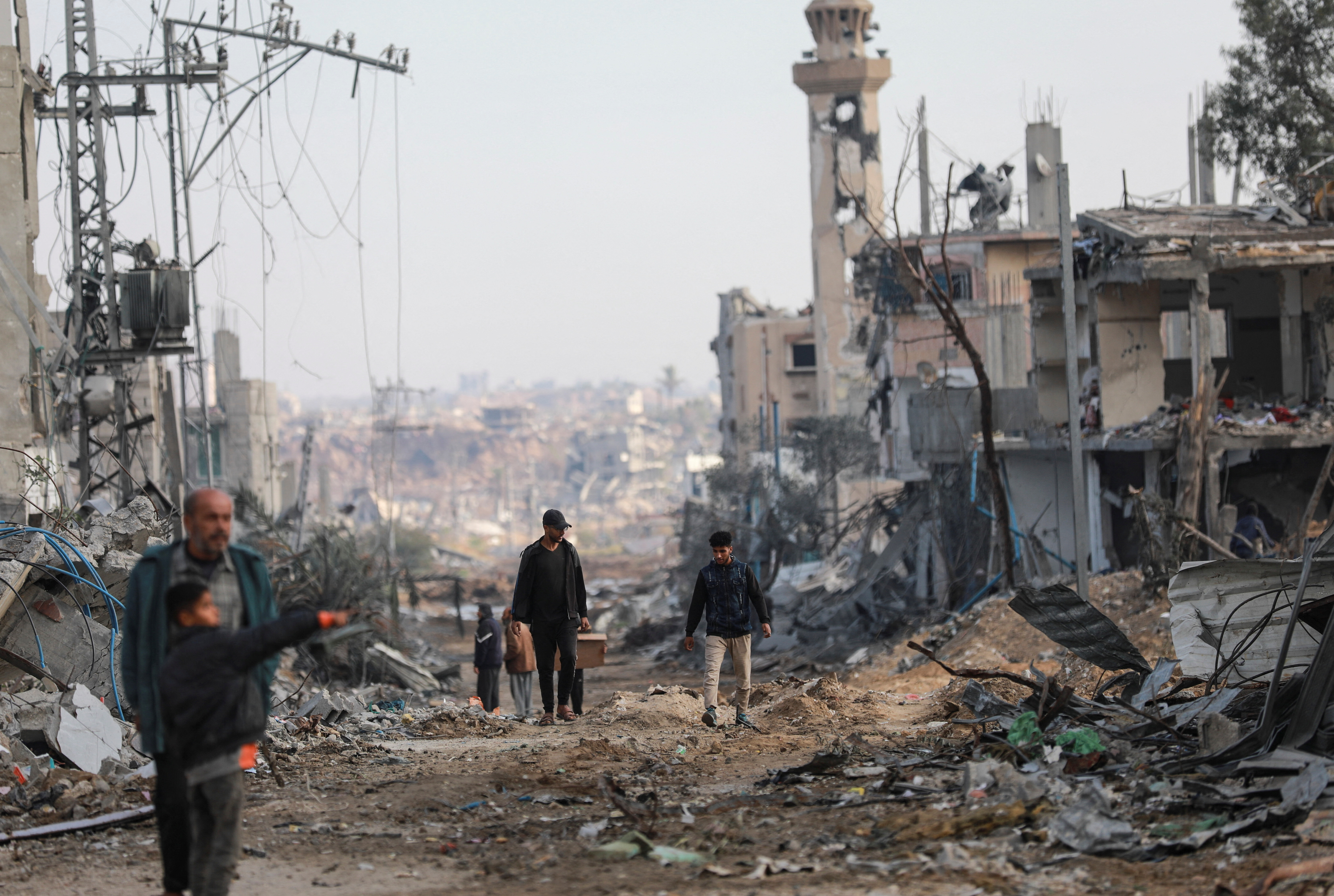 Palestinians walk next to damaged buildings after Israeli forces withdrew from a part of Nuseirat,