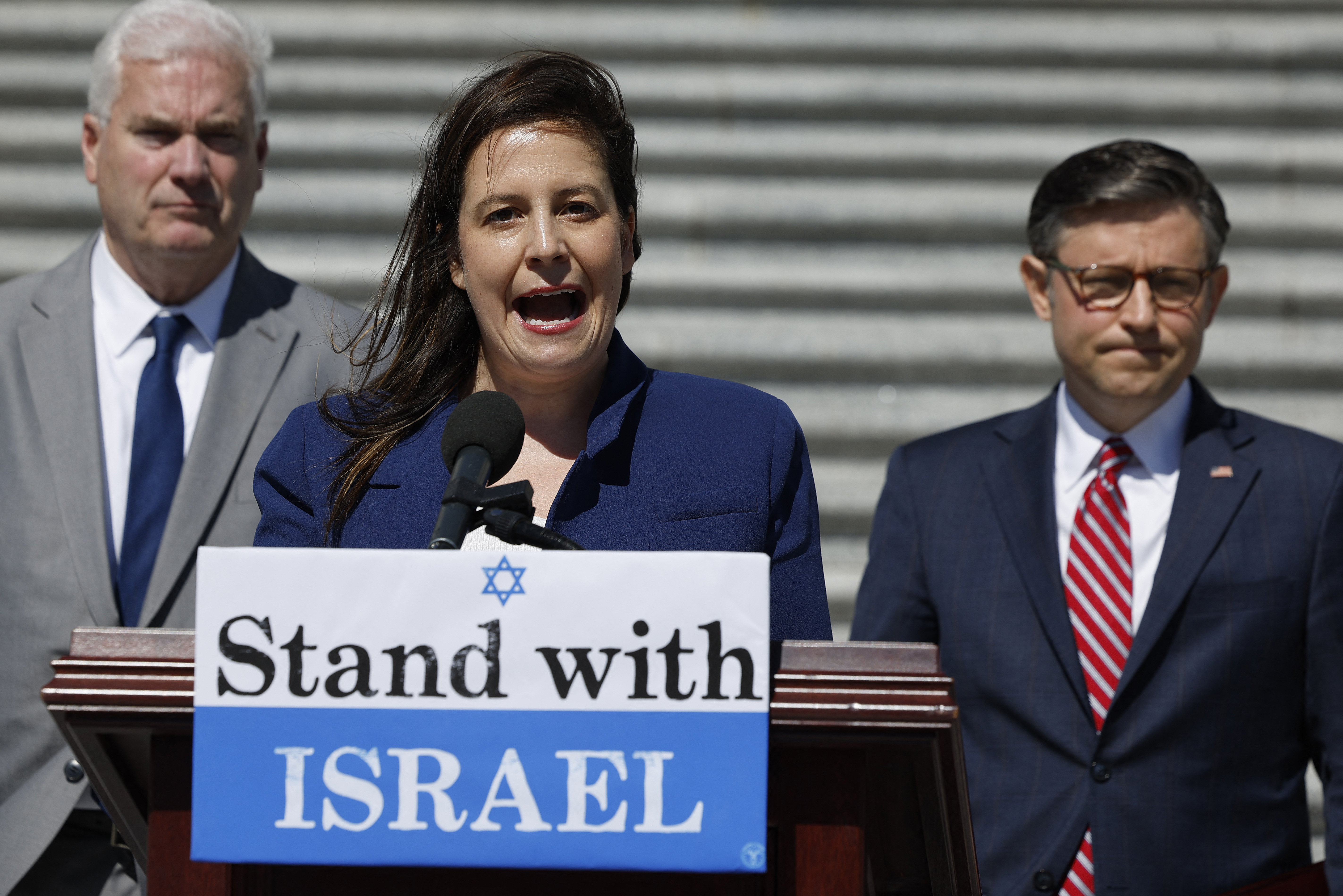 a woman makes a speech behind a podium that says 'stand with israel'