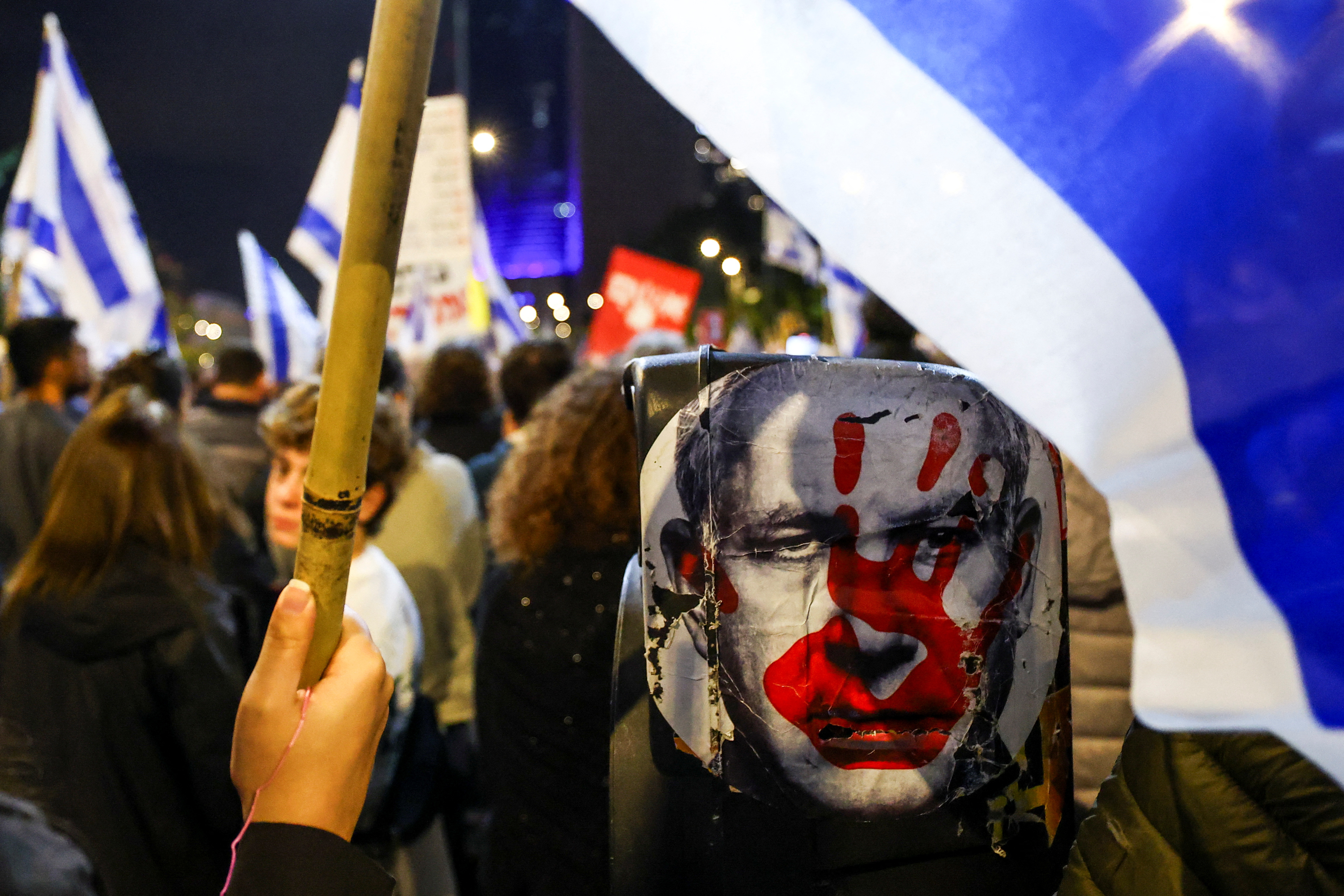 A demonstrator holds an Israeli flag next to an image of Israeli Prime Minister Benjamin Netanyahu, during a protest against the government and to show support for the captives held in Gaza, in Tel Aviv, Israel, on December 21, 2024