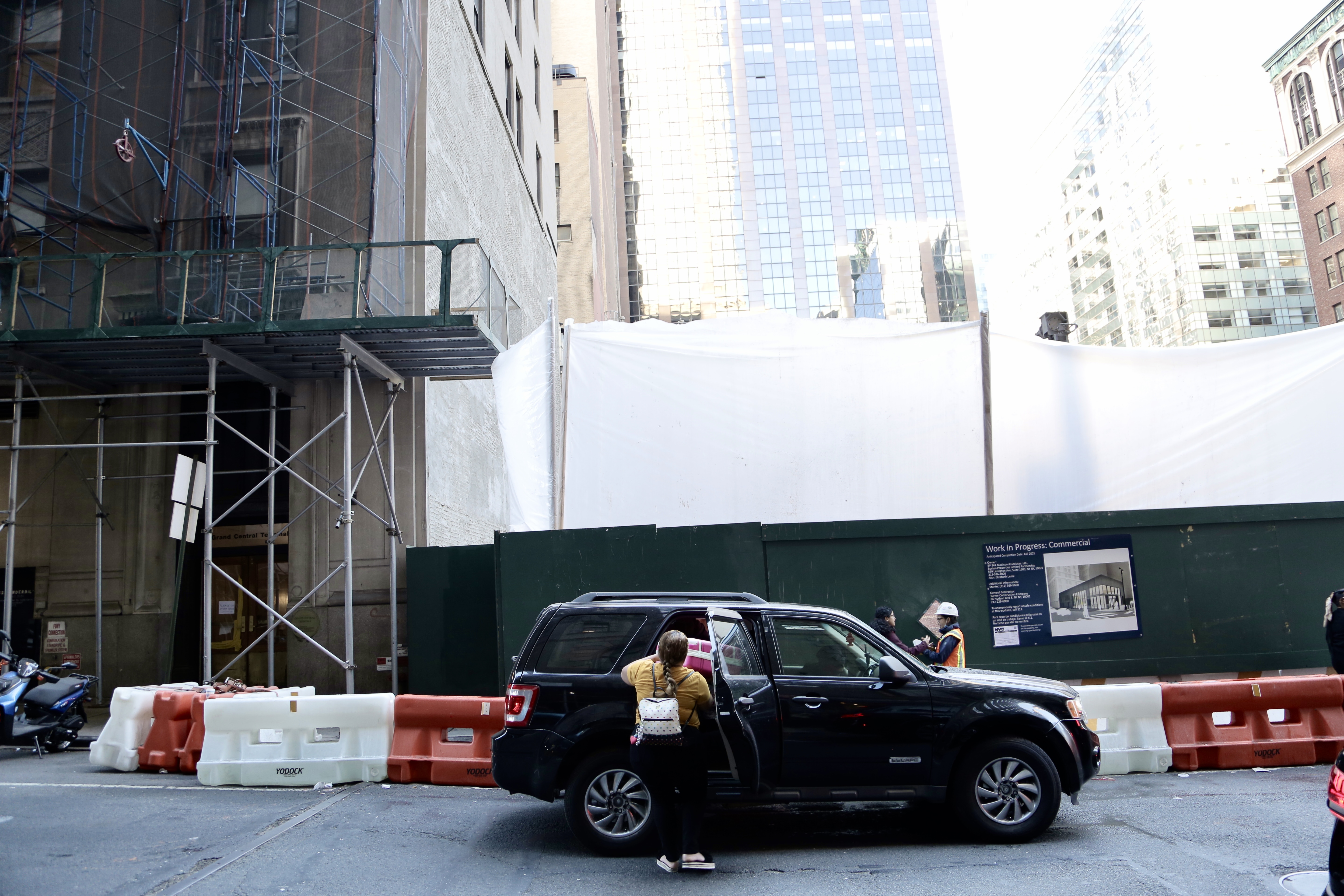 Diana Zarate puts her suitcases into a black SUV.