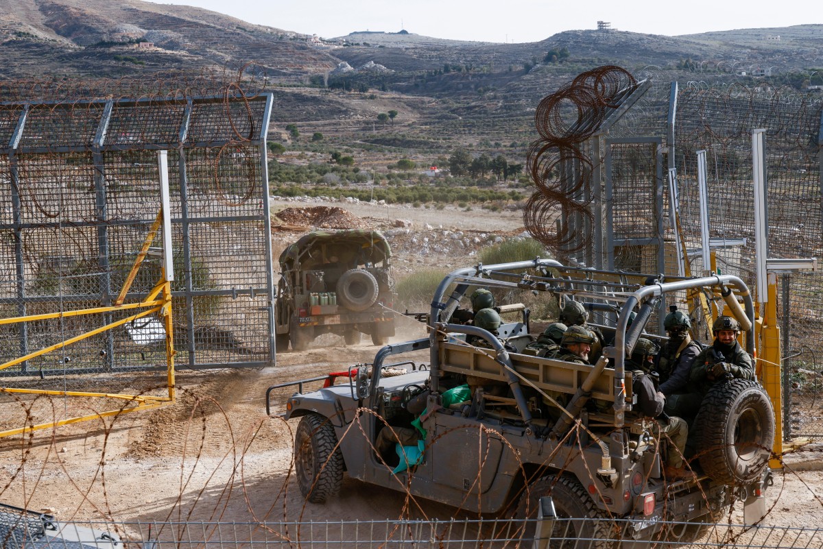 Israeli military vehicles cross the fence to the buffer zone witrh Syria near the Druze village of Majdal Shams in the Israel-annexed Golan Heights on December 10, 2024. (Photo by Jalaa MAREY / AFP)