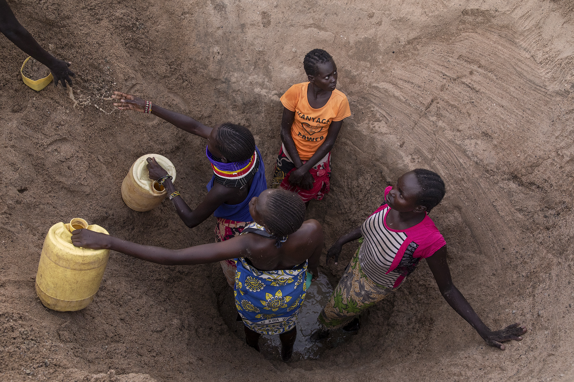 Women fetch water from the dried Kalotumum River in Kerio, located in Turkana County, northwest Kenya on October 17, 2024. Due to the severe drought that is affecting the country, many people are forced to drink water that they fetch from the underground, which is not clean and often causes infections or diseases. According a 2023 UN Water Development Report, groundwater levels are falling, forcing some communities to drill wells twice as deep as they were a decade ago. [Alessio Paduano/Al Jazeera]