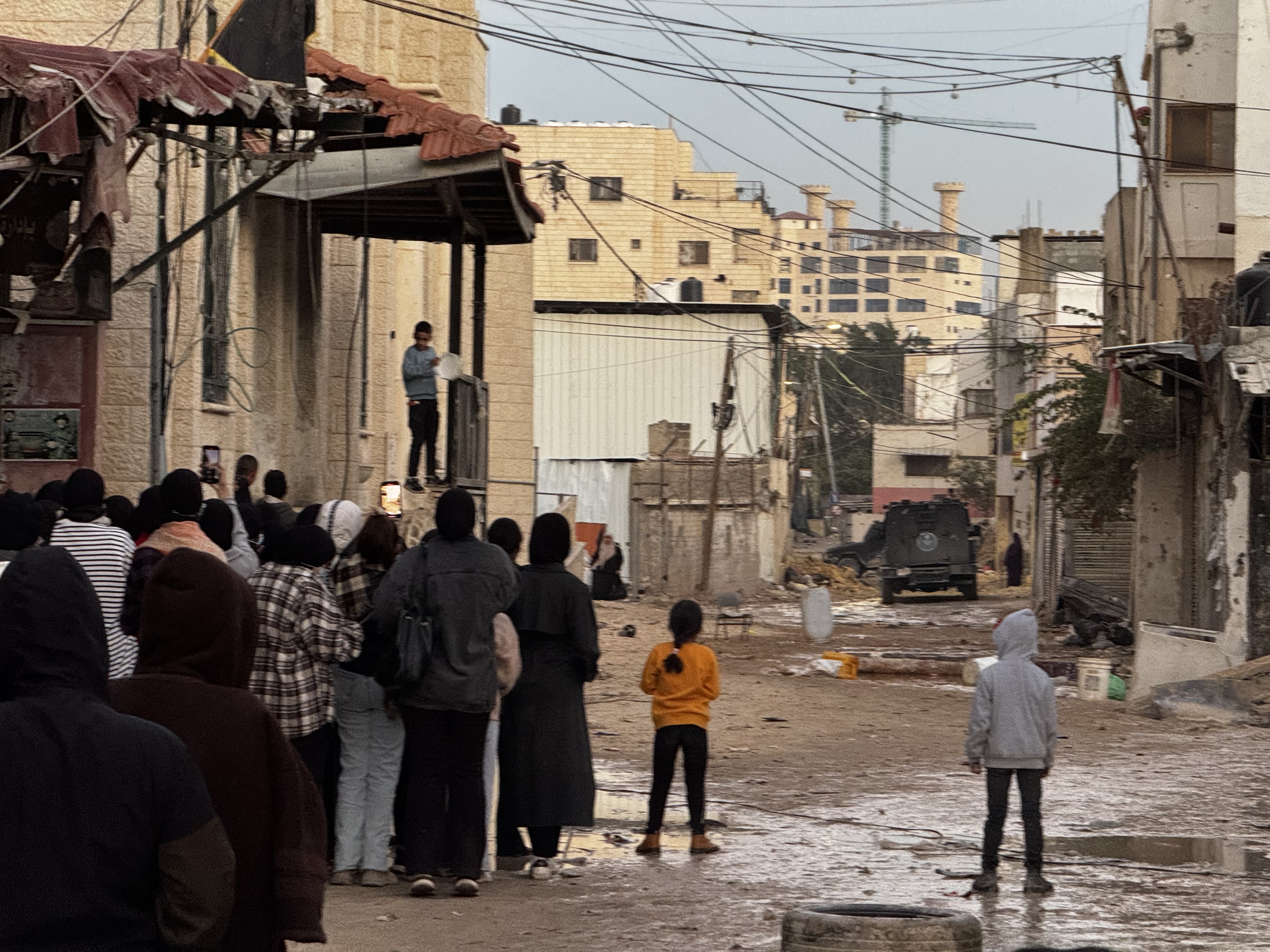 Palestinian locals look on at armoured car