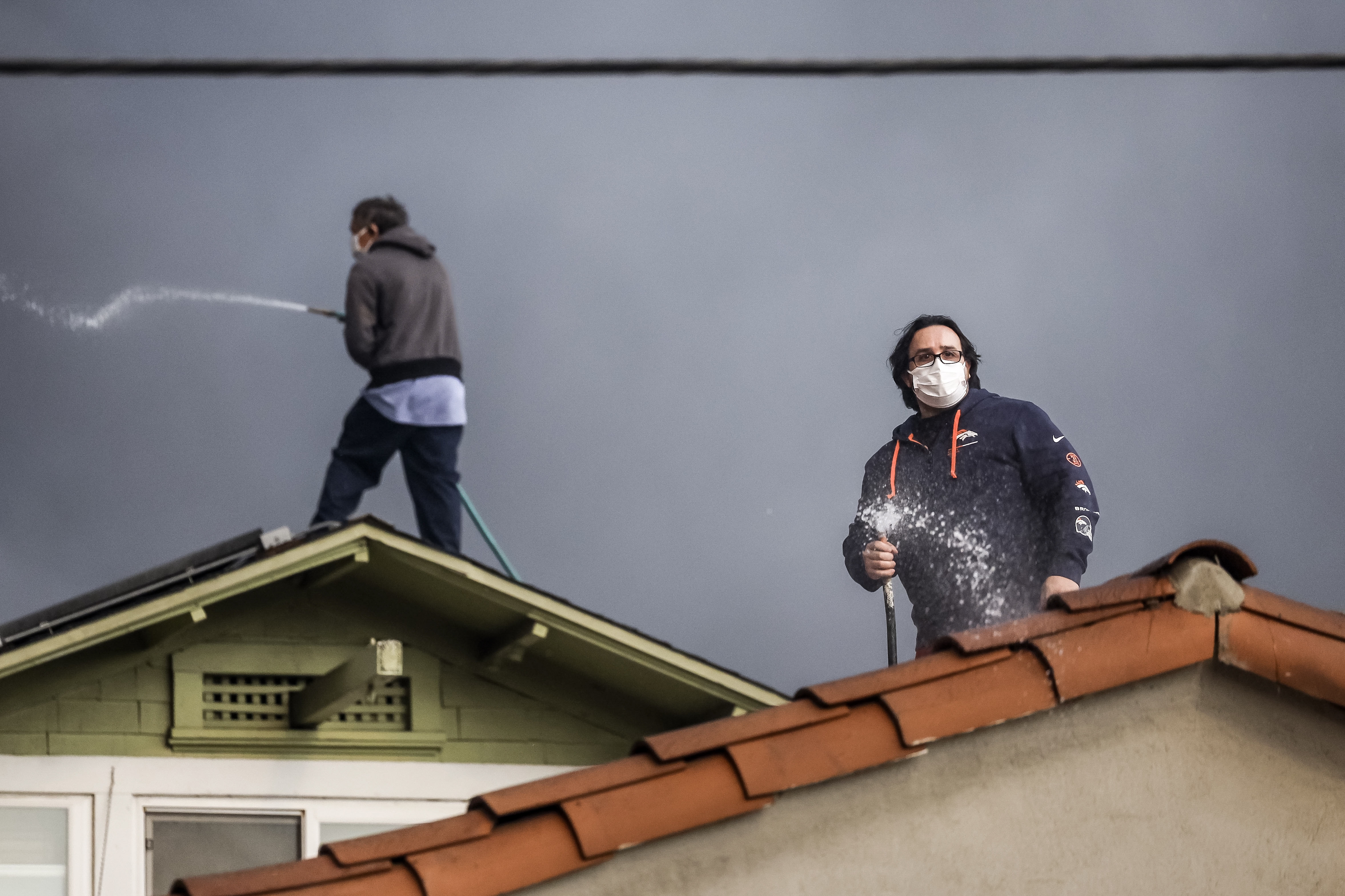 People use garden hoses to protect a roof from embers as the Eaton wildfire burns nearby in Altadena, California, USA, 08 January 2025.