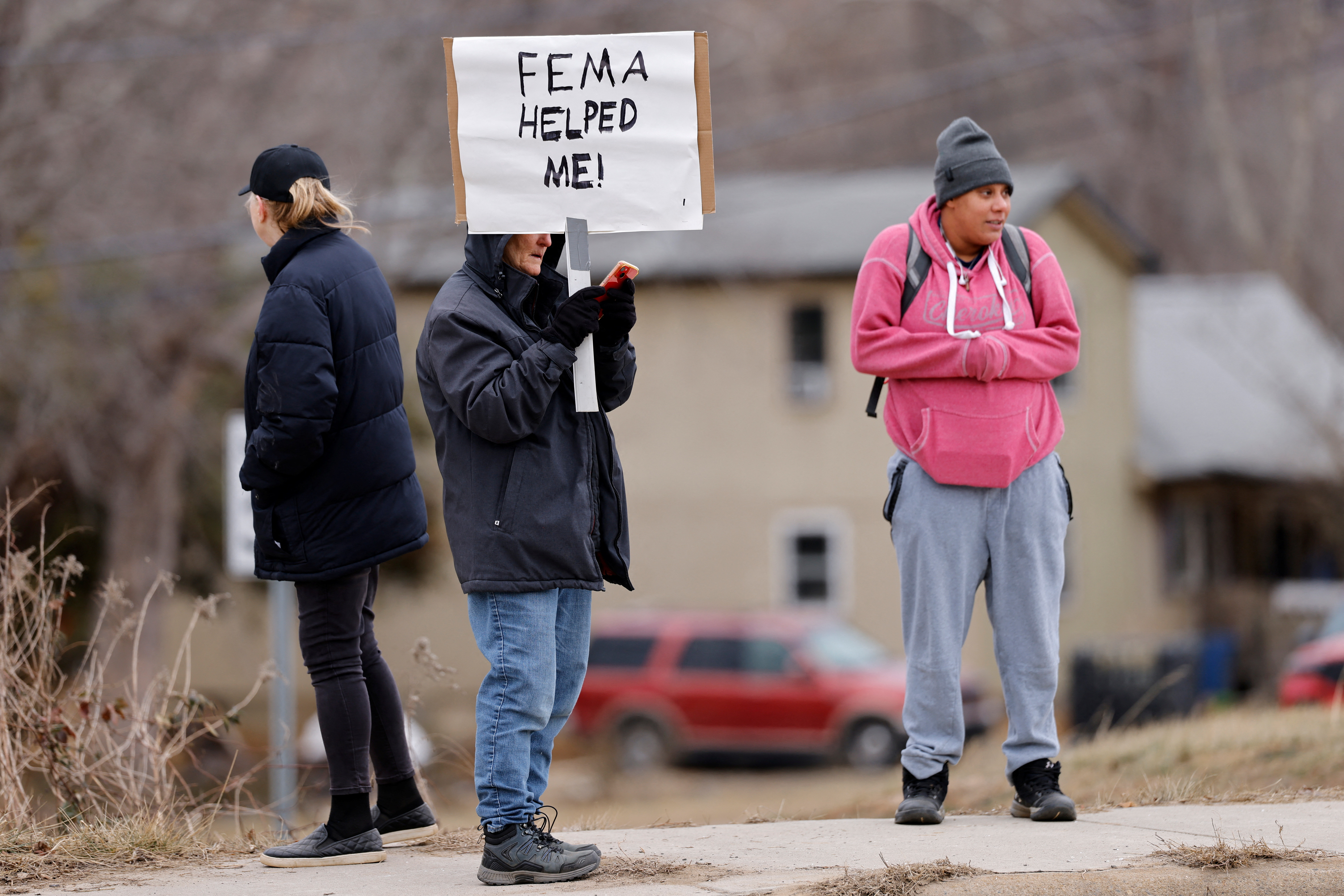 A person holds up a sign in North Carolina that reads "FEMA helped me"