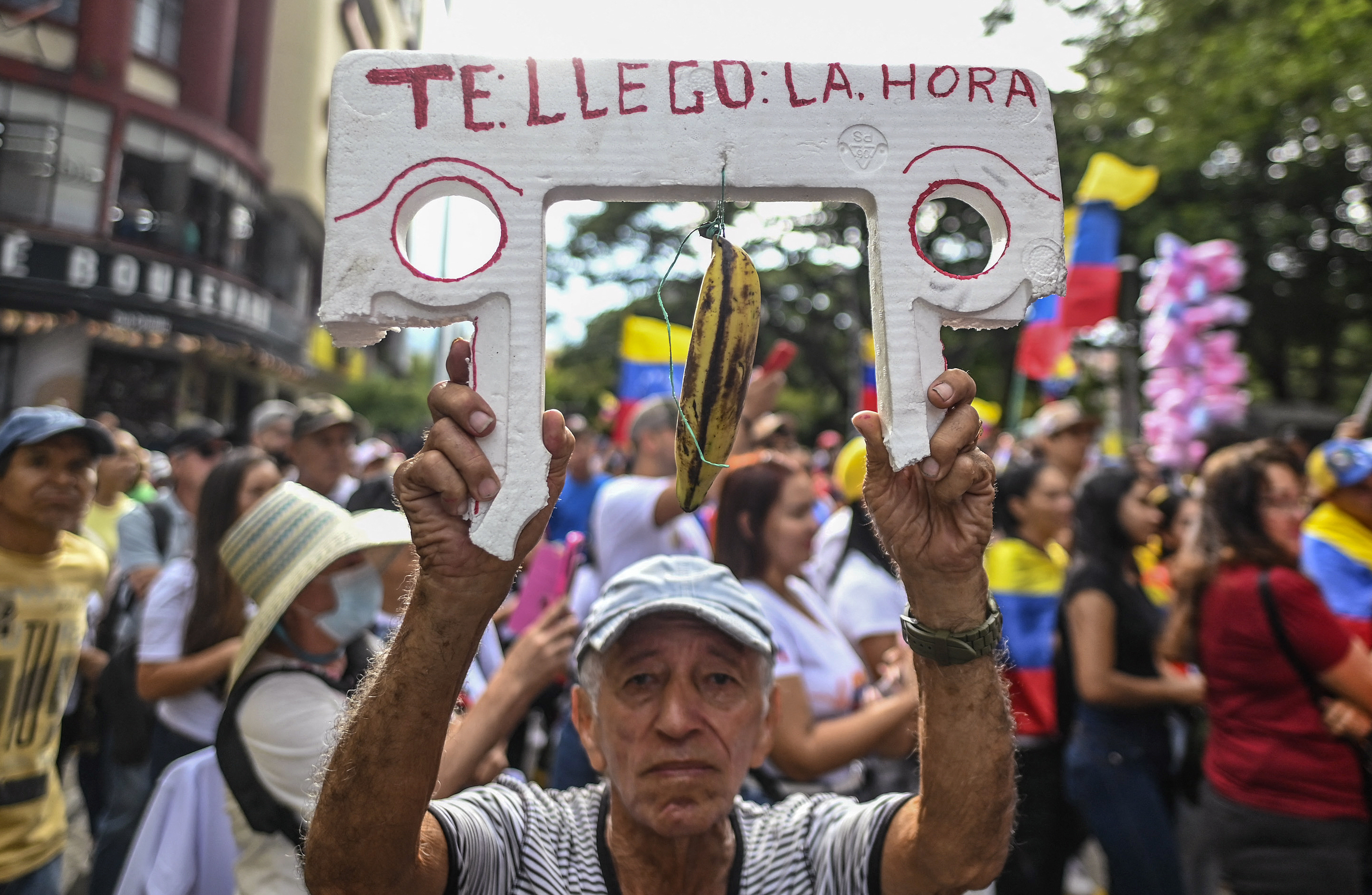 A man carries a banner that reads 'your time has come' with a banana known in colombia as 'maduro' depicting Venezuela's President Nicolas Maduro during a protest called by the opposition on the eve of the presidential inauguration in Cali, Colombia on January 9