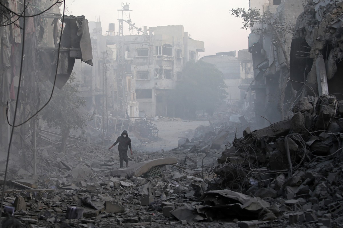 A man walks through the rubble of buildings destroyed in Israeli airstrikes