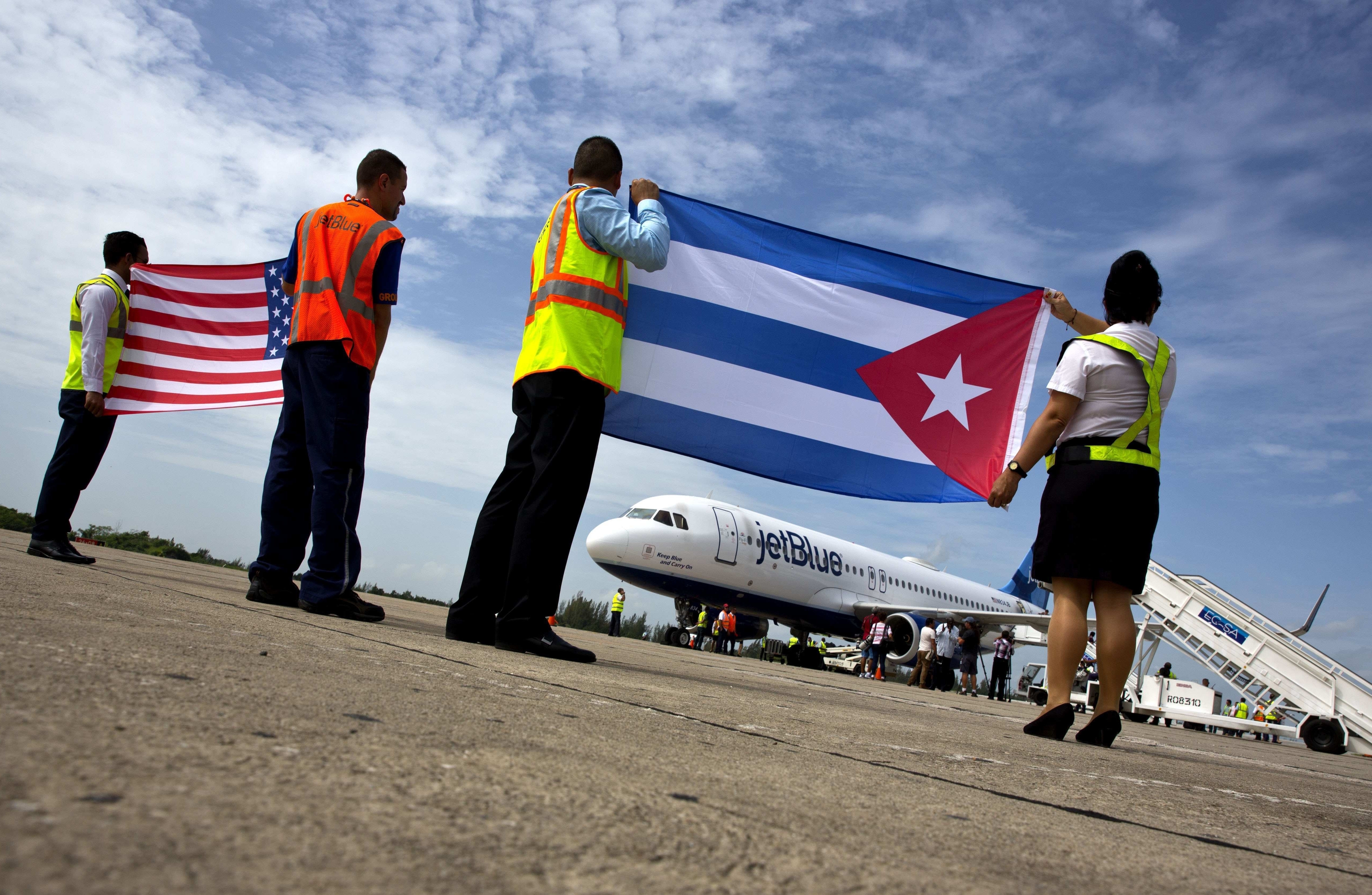 JetBlue employees hold up Cuban and US flags on the tarmac after commercial flights are restored in 2016