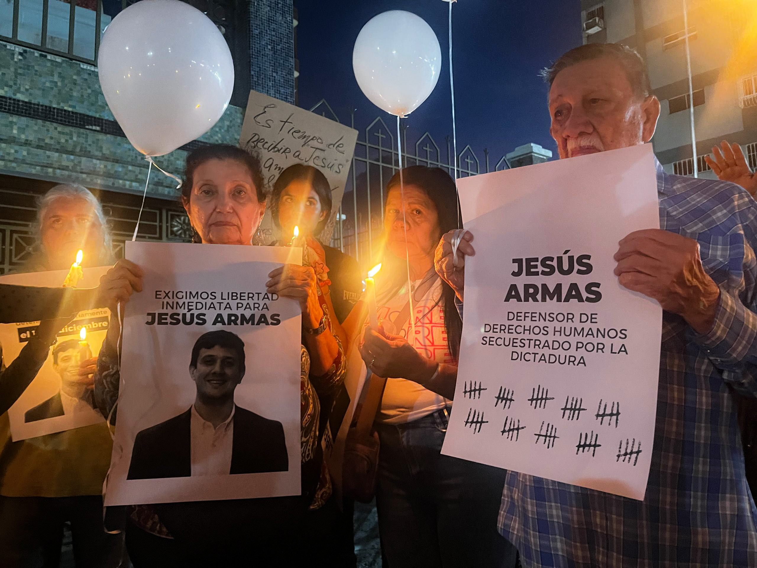 Friends and family of Jesus Armas hold up posters calling for his release