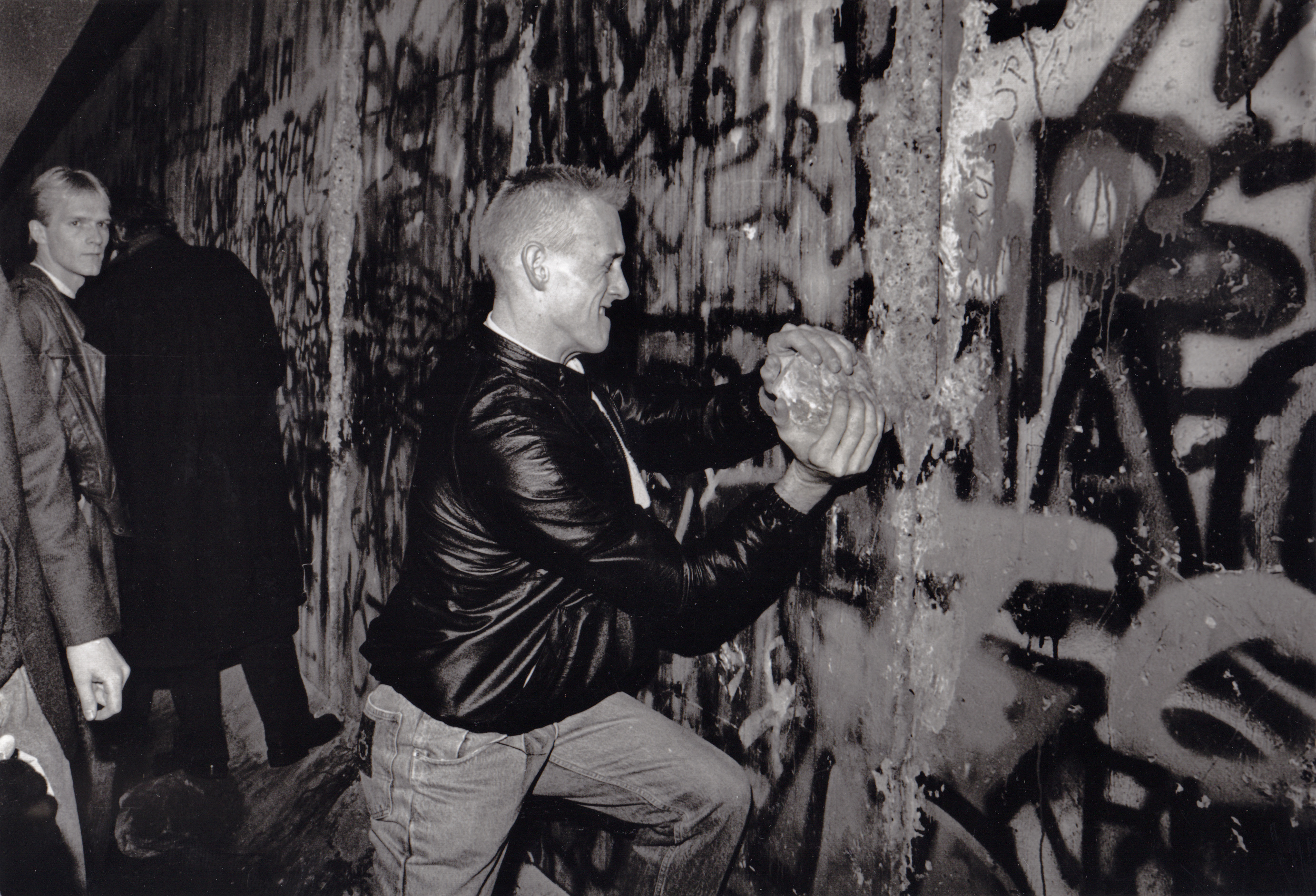 A youth takes a large piece of the Berlin Wall in his hands as he tries to hammer a hole in the wall with it in late 1989 [Rich Lipski/The Washington Post via Getty Images]