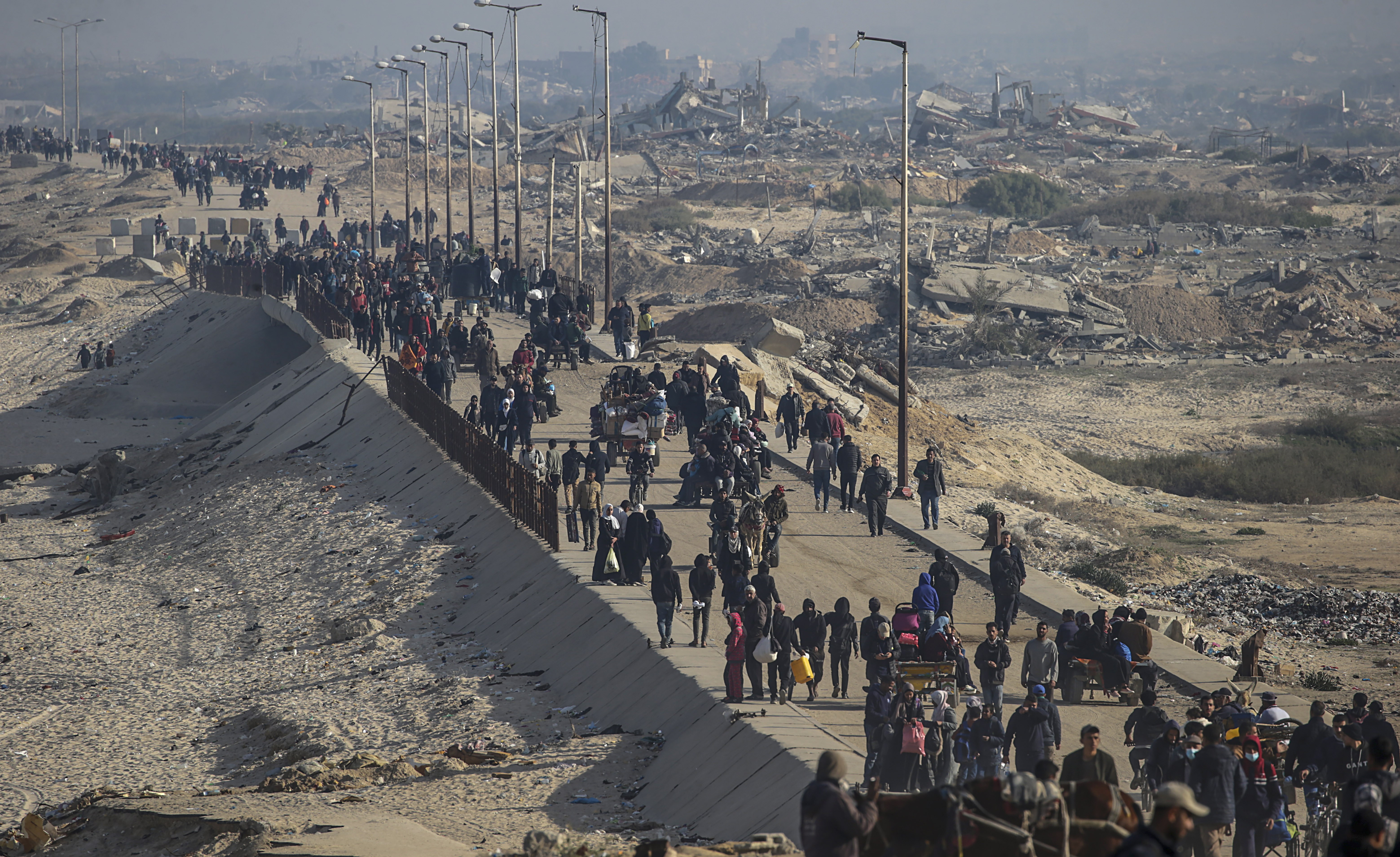 Palestinians make their way amid the rubble of destroyed buildings on al-Rashid Street, Gaza
