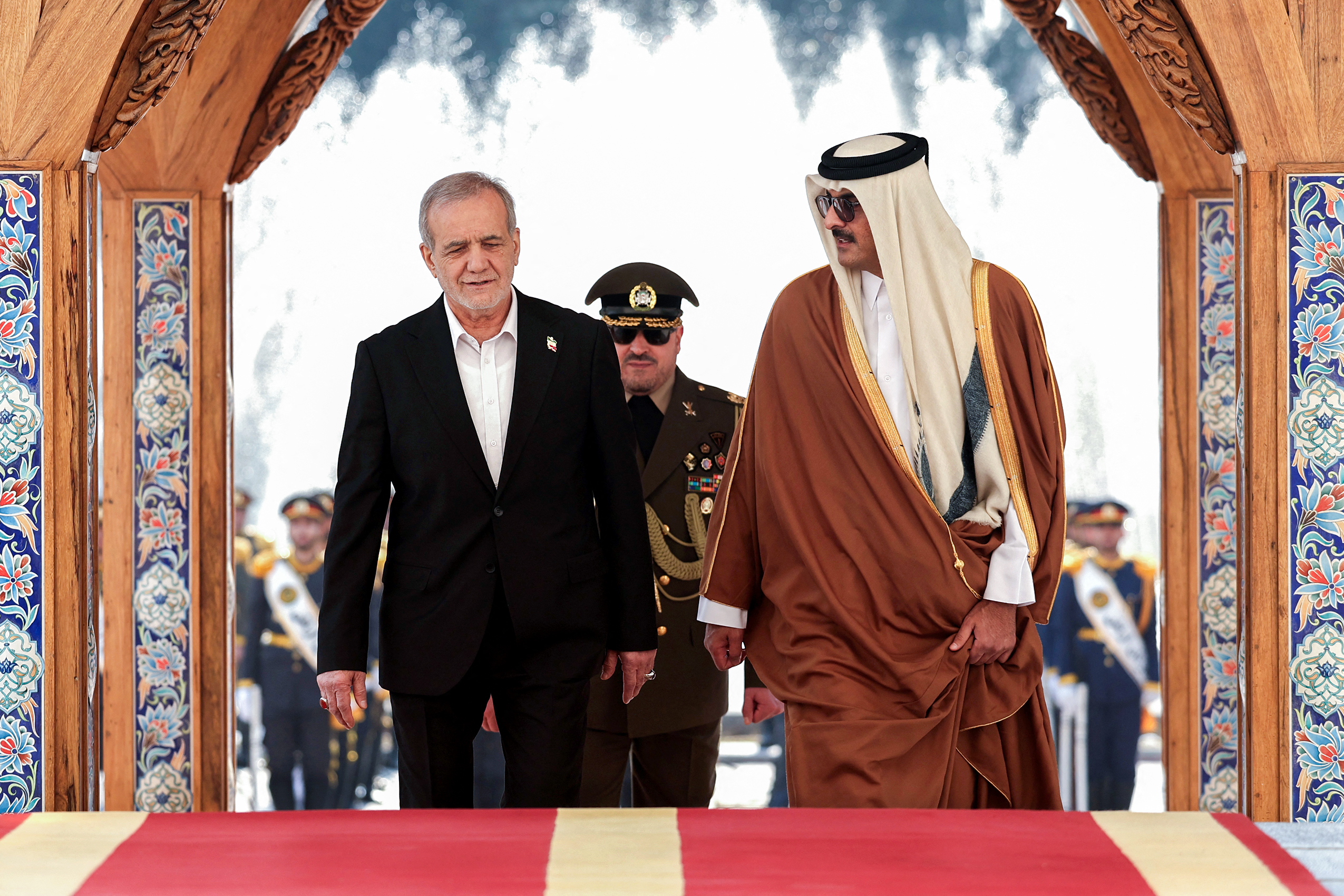 This handout picture provided by the Iranian presidency shows Iran's president Masoud Pezeshkian (L) walking with Qatar's Emir Sheikh Tamim bin Hamad Al-Thani during a welcome ceremony at the presidential palace in Tehran on February 19, 2025. (Photo by Iranian Presidency / AFP) / === RESTRICTED TO EDITORIAL USE - MANDATORY CREDIT "AFP PHOTO / HO / IRANIAN PRESIDENCY" - NO MARKETING NO ADVERTISING CAMPAIGNS - DISTRIBUTED AS A