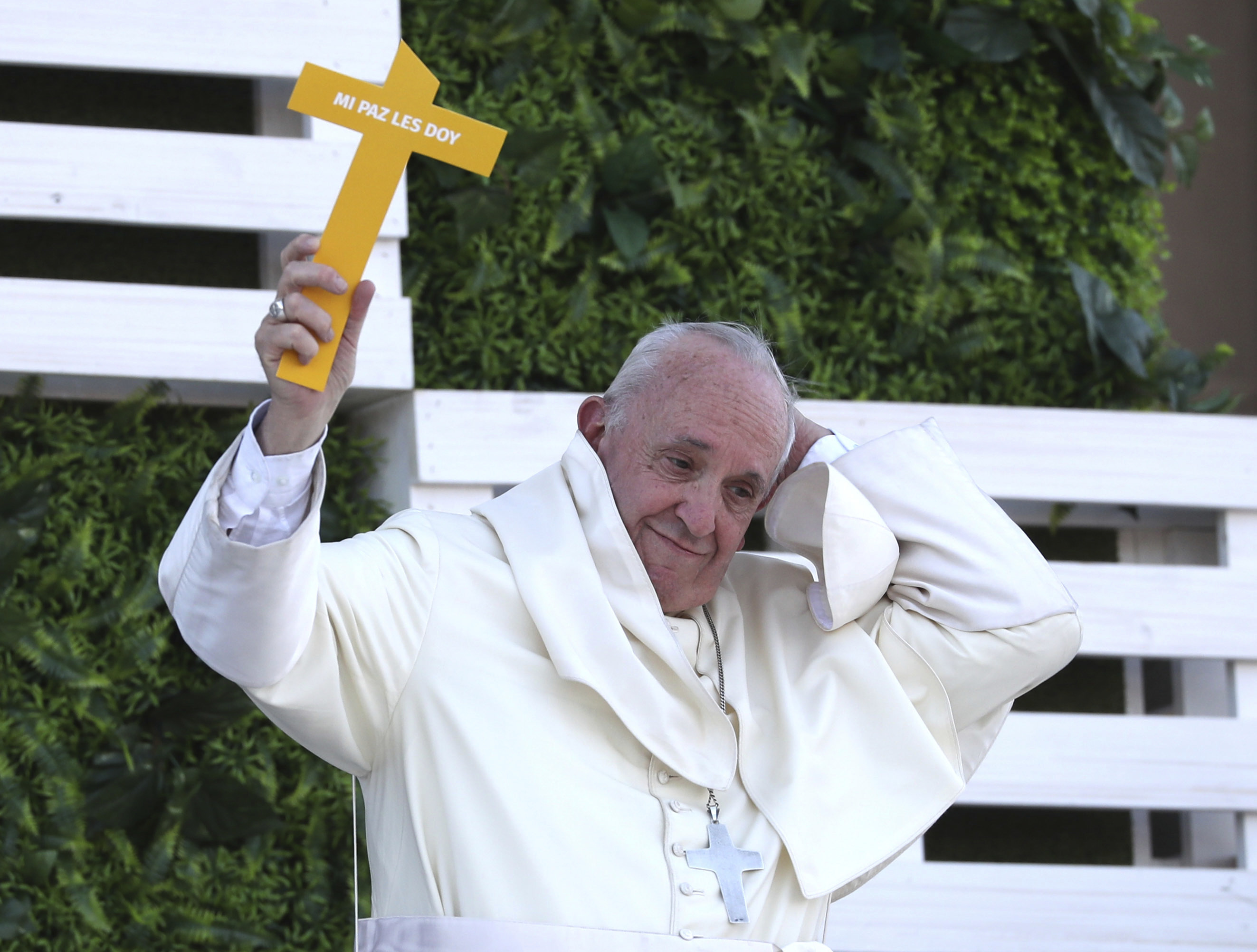 Pope Francis loses his skull cap as he holds up a cross that reads in Spanish ‘I give you my peace’ upon arrival to meet youths at the Shrine of Maipu in Santiago, Chile