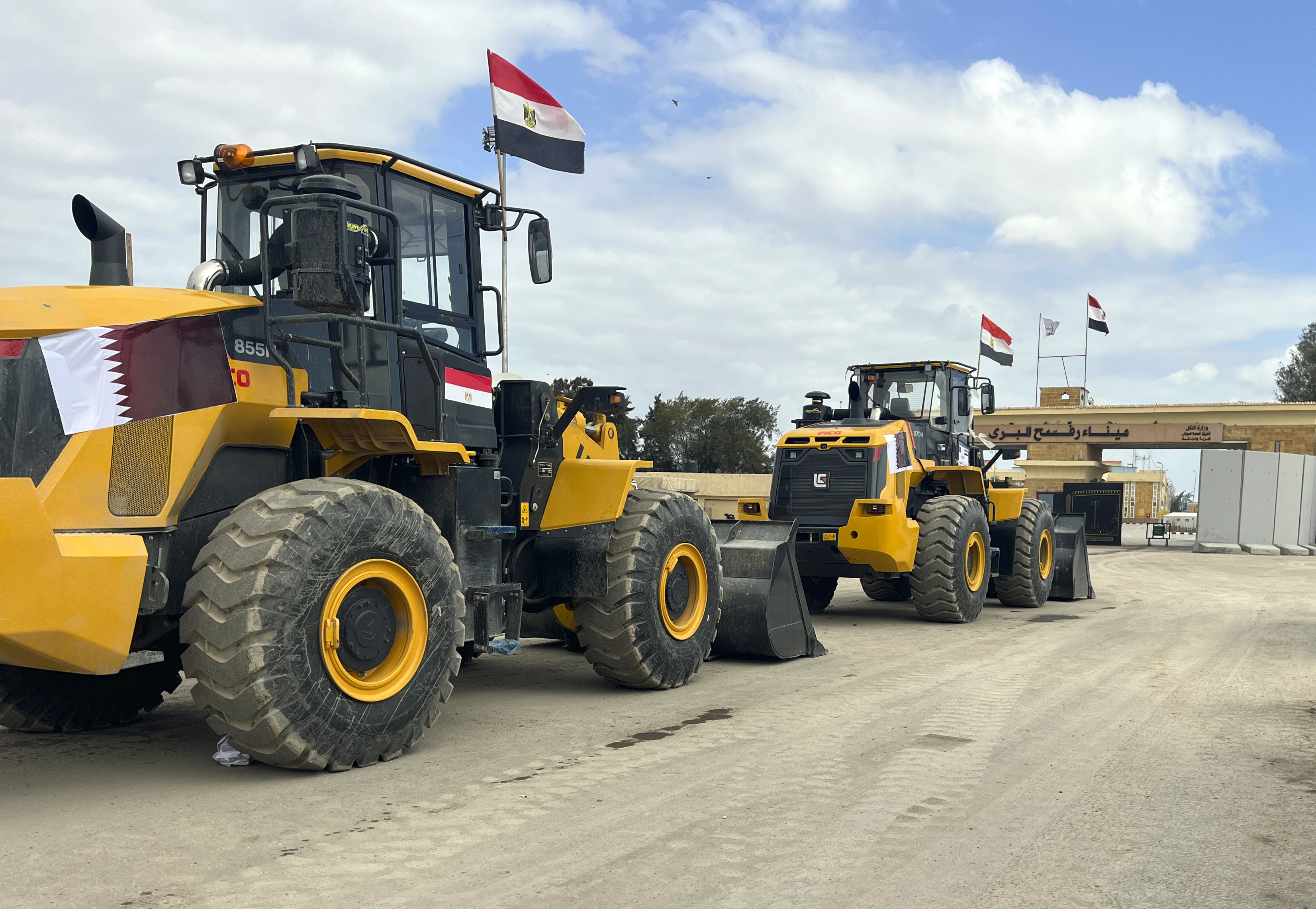 Bulldozers with Egyptian and Qatar flags wait to enter Gaza at the Rafah border crossing between Egypt and the Gaza Strip, Thursday, Feb. 13, 2025. (AP Photo/Mohamed Arafat)