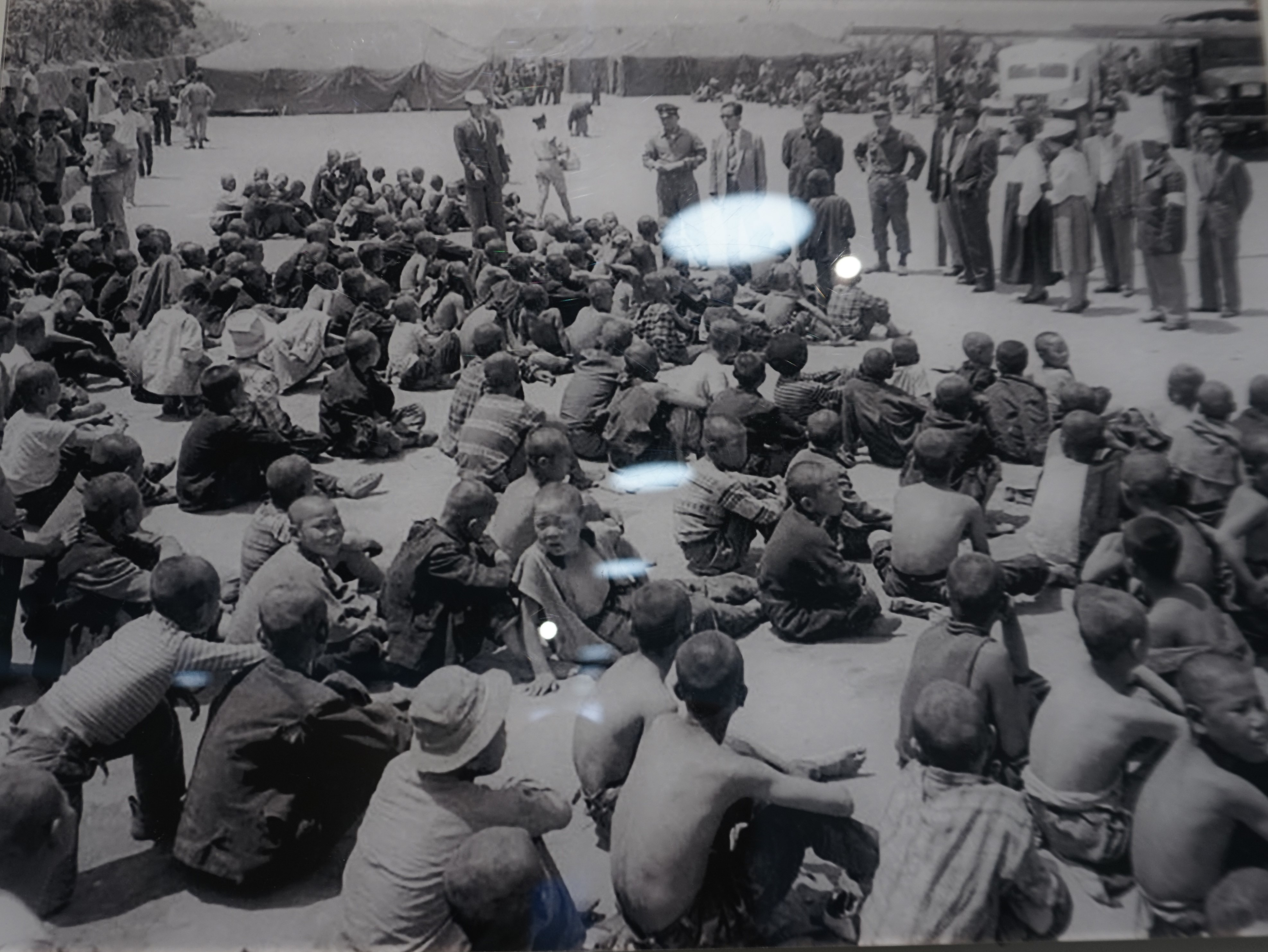 A photo of an original image of child inmates sitting in front of government officials at Seon-gam Academy in the 1960s
