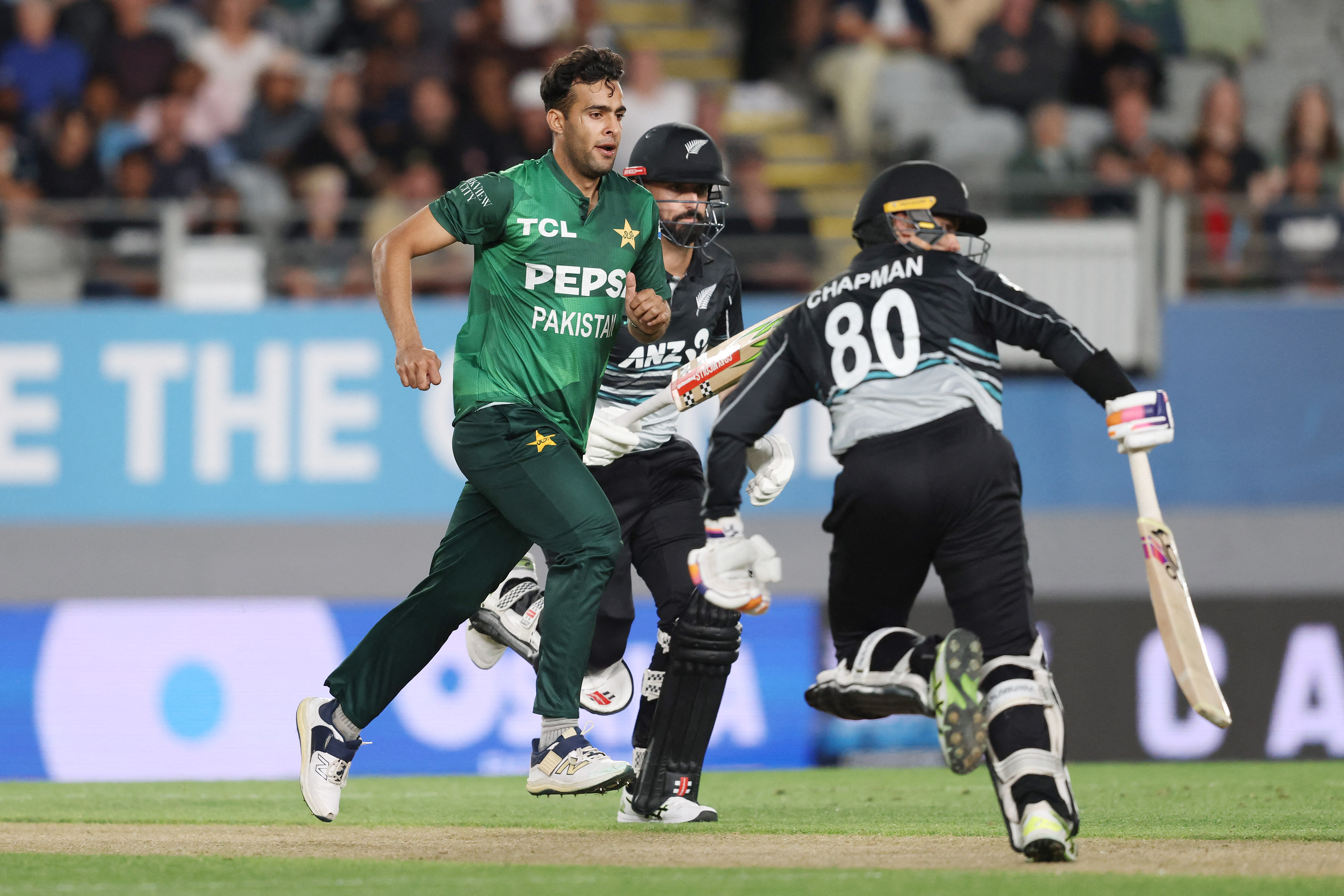 Pakistan's Abbas Afridi (L) chases the ball between New Zealands players Daryl Mitchell (C) and Mark Chapman (R) during the third T20 international cricket match between New Zealand and Pakistan at Eden Park in Auckland on March 21, 2025. (Photo by Michael Bradley / AFP)
