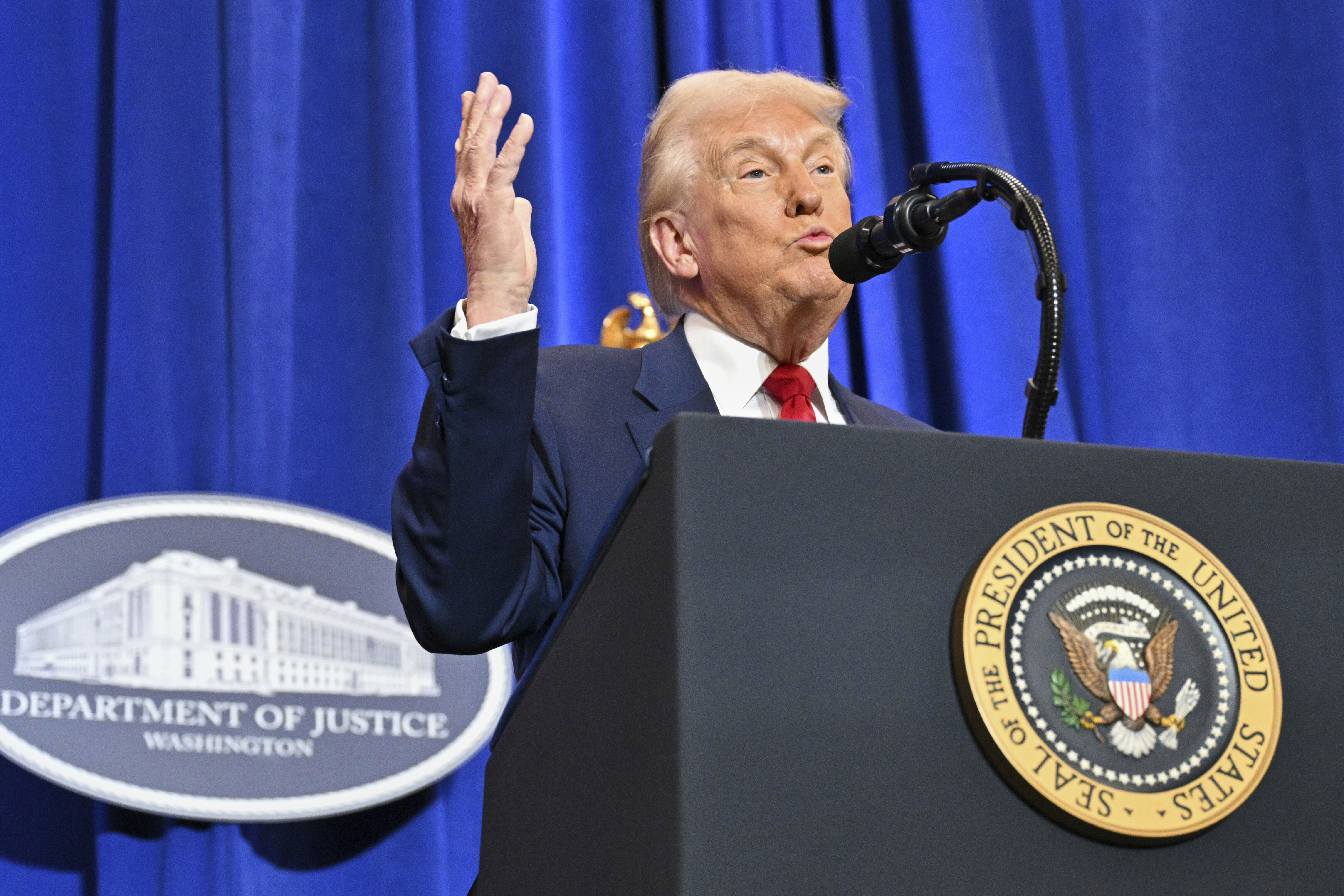 Donald Trump gestures behind a podium at the Justice Department.