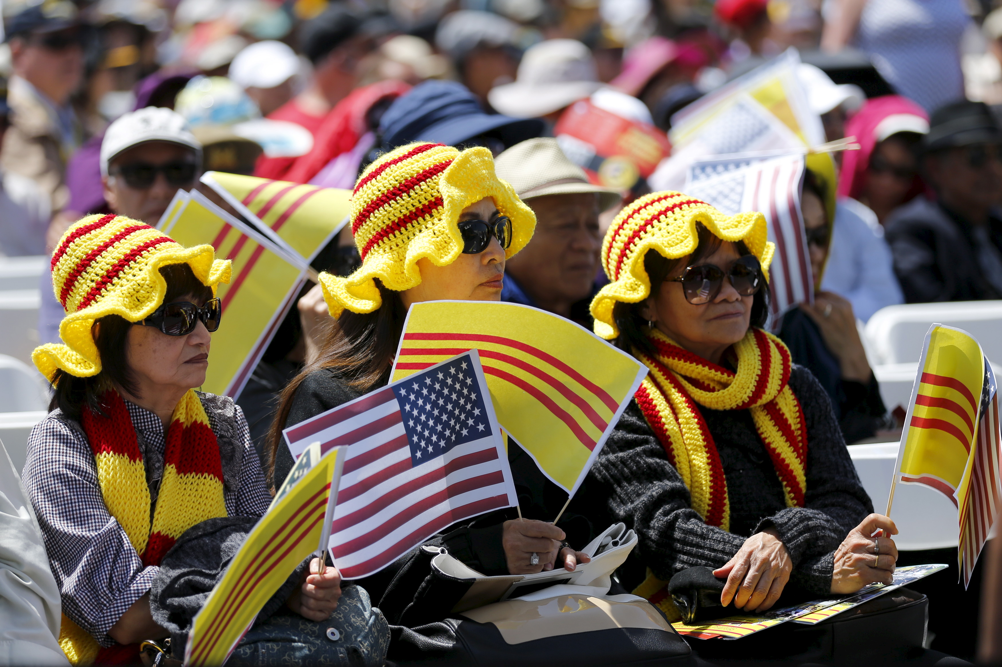 Visiting members of the Vietnamese community hold the flag of former South Vietnam as they attend a ceremony on the flight deck of the USS Midway as the ship commemorates the 40th Anniversary of Operation Frequent Wind and the fall of Saigon in San Diego, California, United States April 26, 2015. REUTERS/Mike Blake