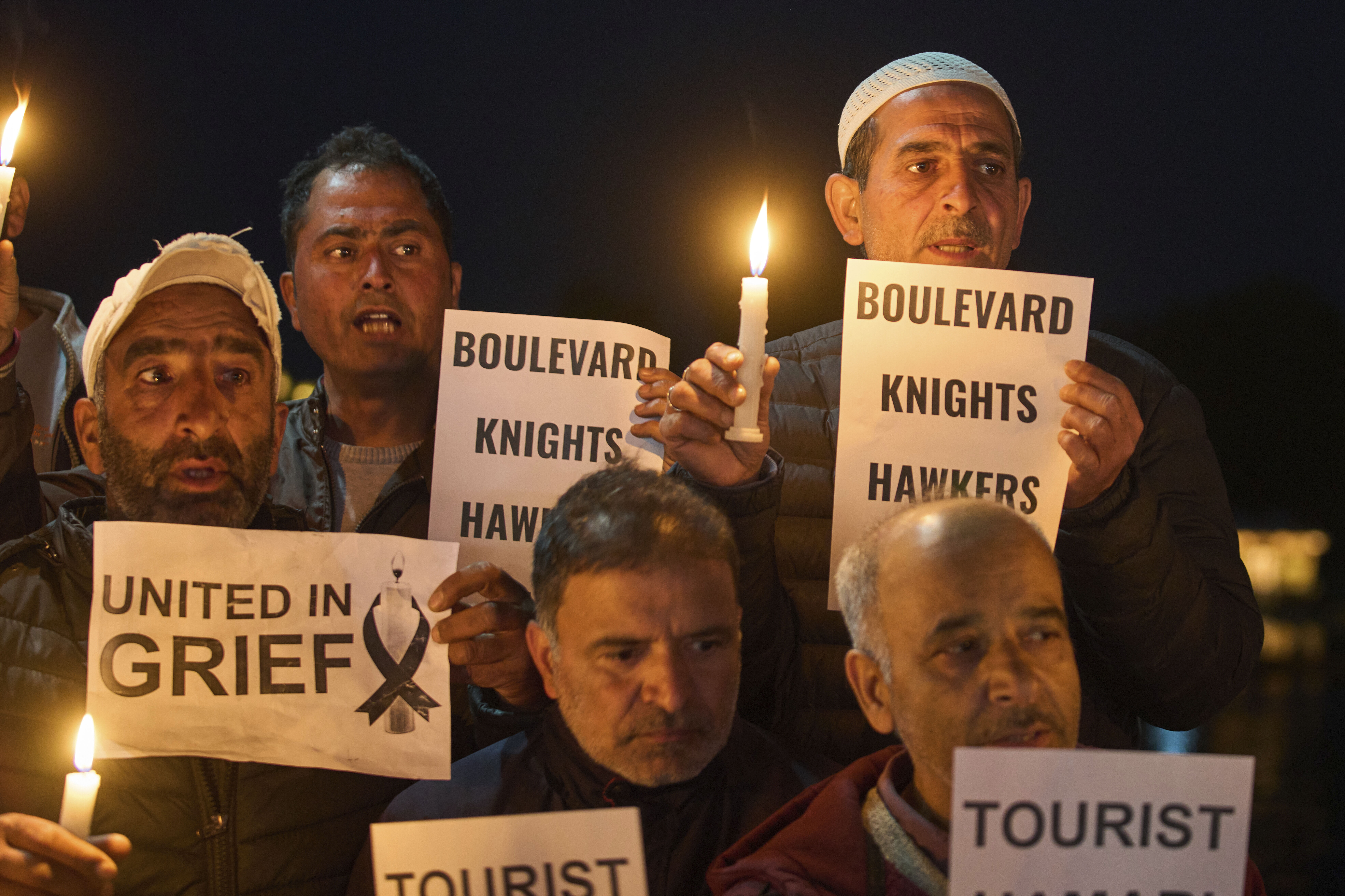 People hold signs and candles during a vigil for the victims of the Kashmir attack