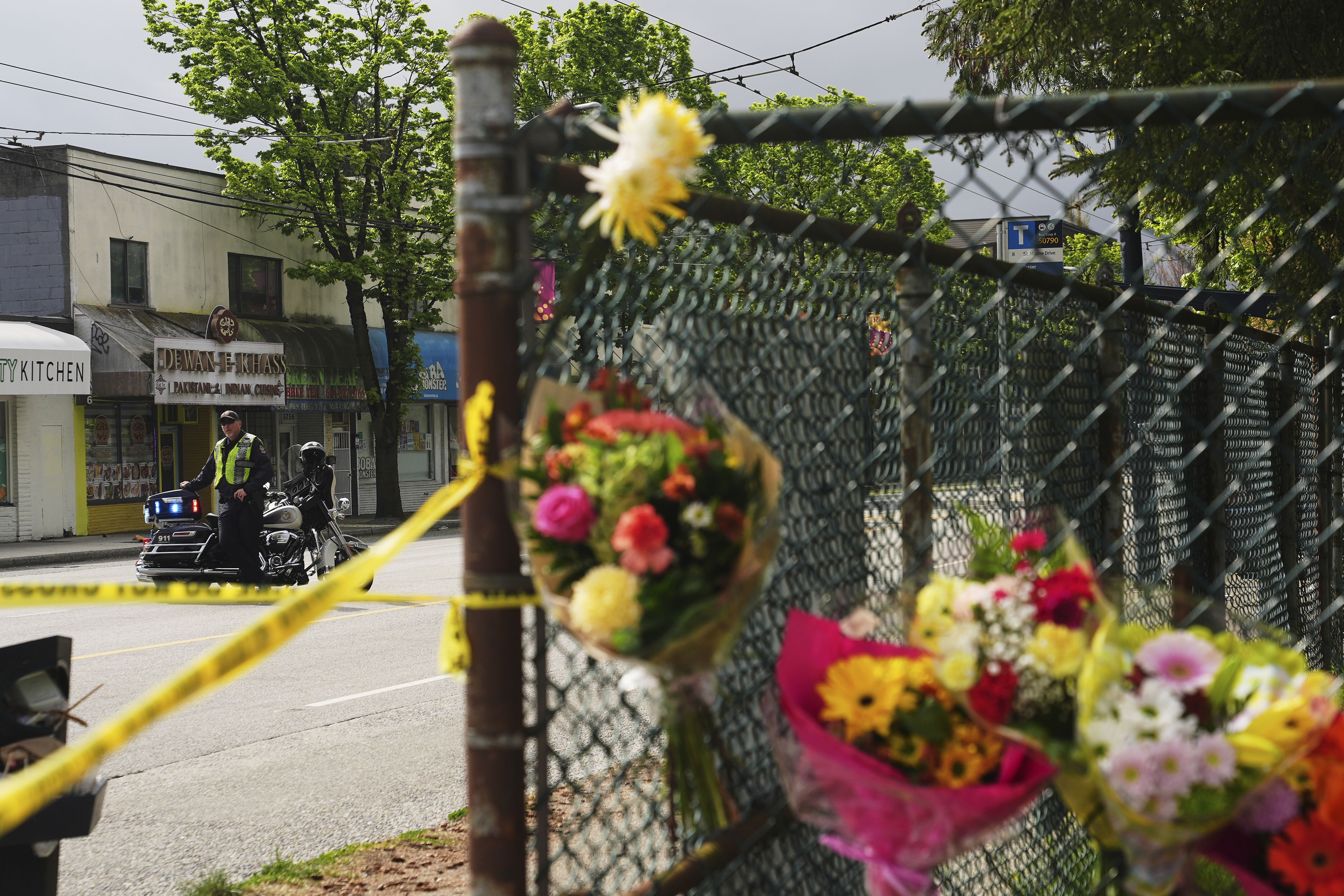 A Vancouver Police officer monitors the scene as a memorial of flowers grows the day after a driver killed multiple people during a Filipino community festival Sunday, April 27, 2025, in Vancouver, British Columbia. (AP Photo/Lindsey Wasson)