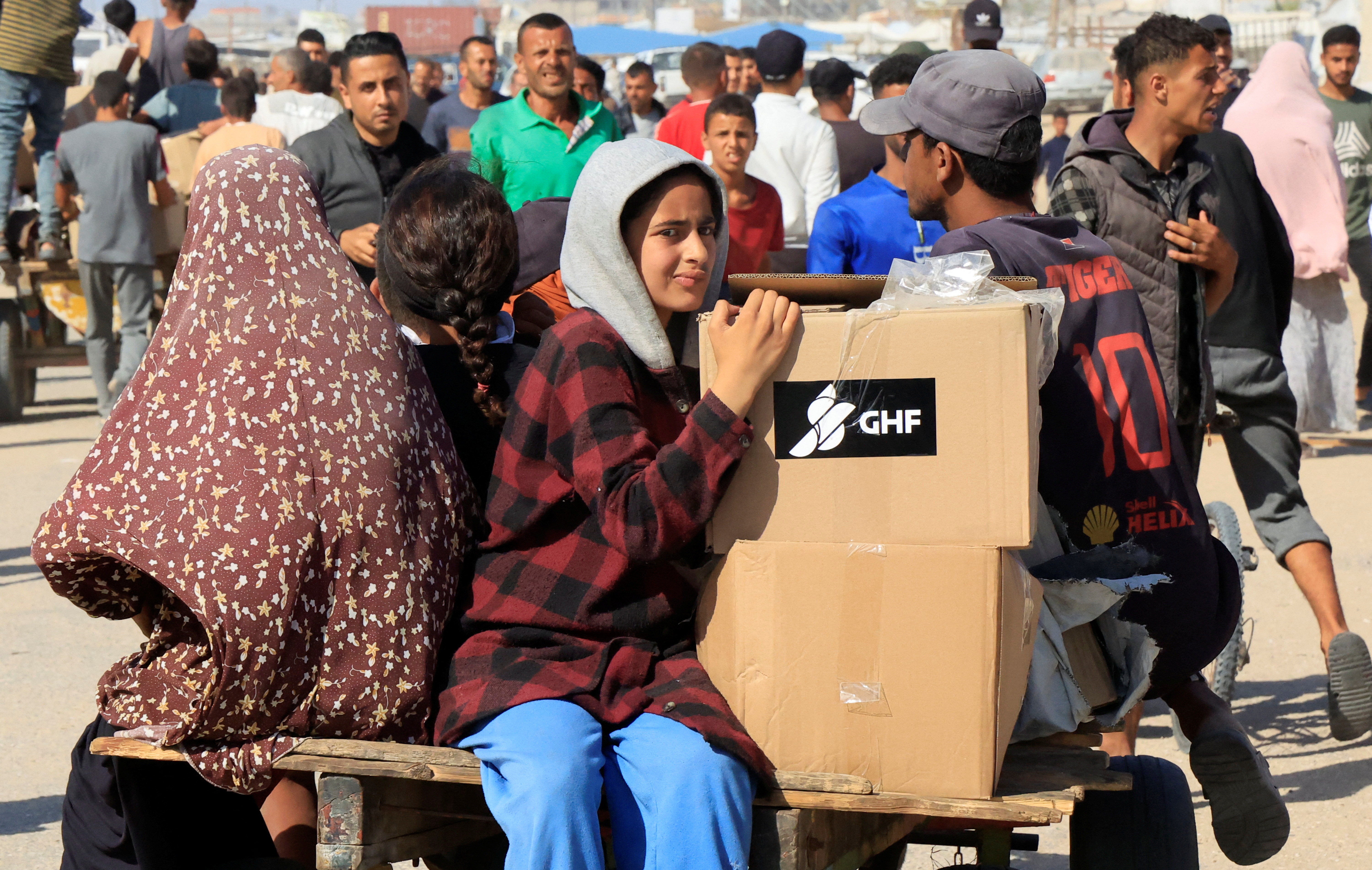 A child leans against two stacked cardboard boxes labelled GHF