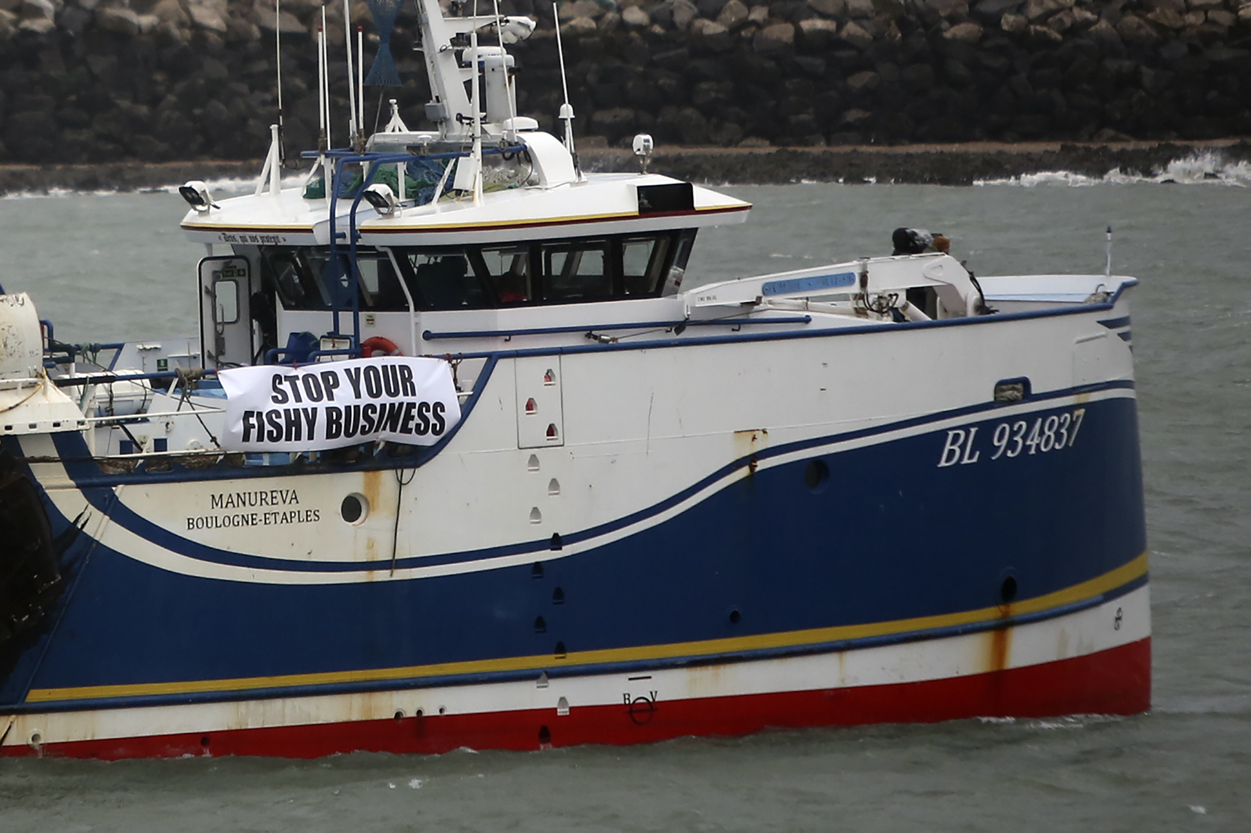 French fishing boats block the entrance to the port of Calais, northern France, Friday, Nov. 26, 2021. French fishing crews are threatening to block French ports and traffic under the English Channel on Friday to disrupt the flow of goods to the U.K., in a dispute over post-Brexit fishing licenses. (AP Photo/Rafael Yaghobzadeh)