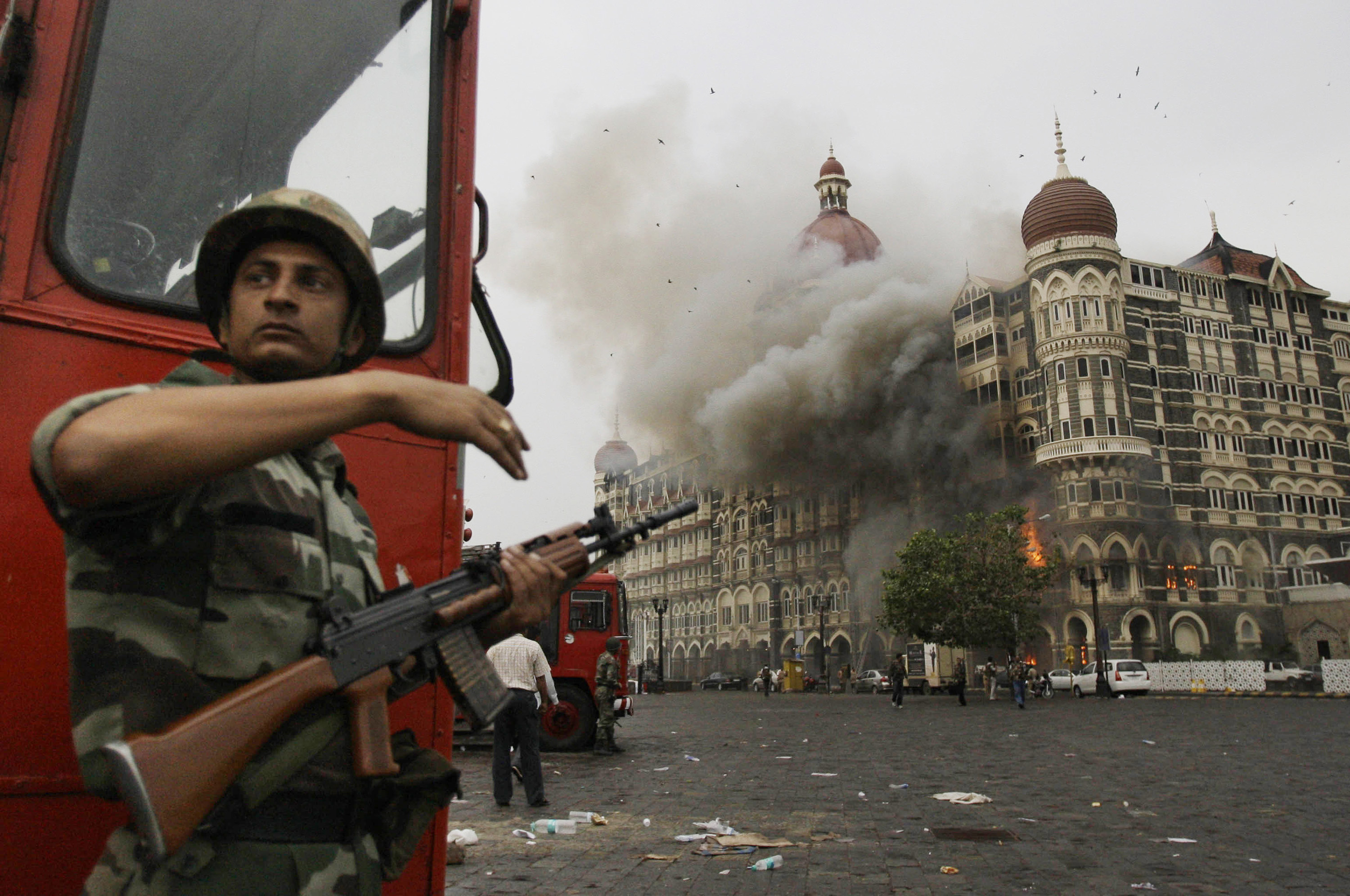 An Indian soldier takes cover as the Taj Mahal hotel burns during gun battle between Indian military and militants inside the hotel in Mumbai, India, Nov. 29, 2008. 