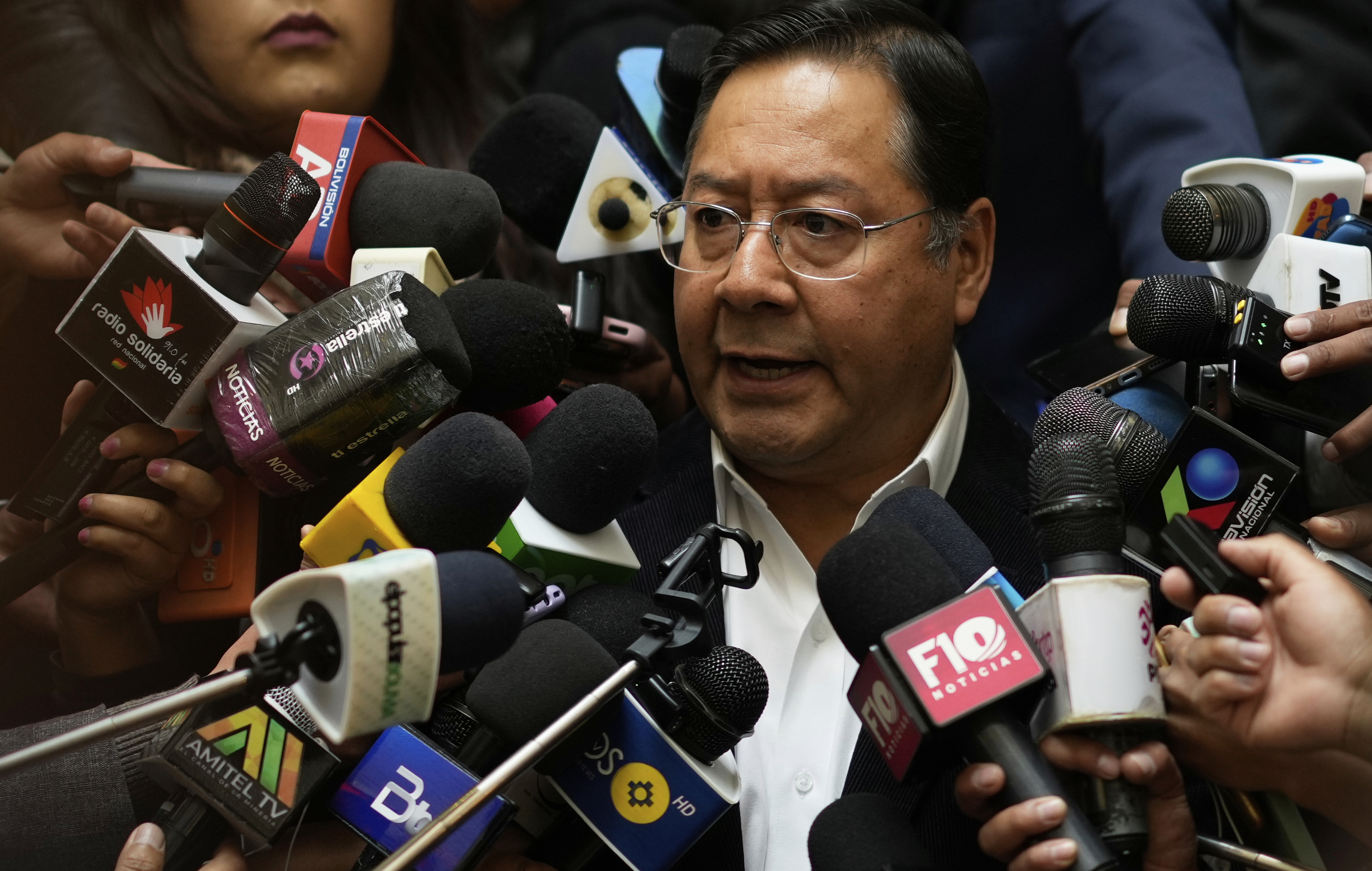 Luis Arce surrounded by microphones.