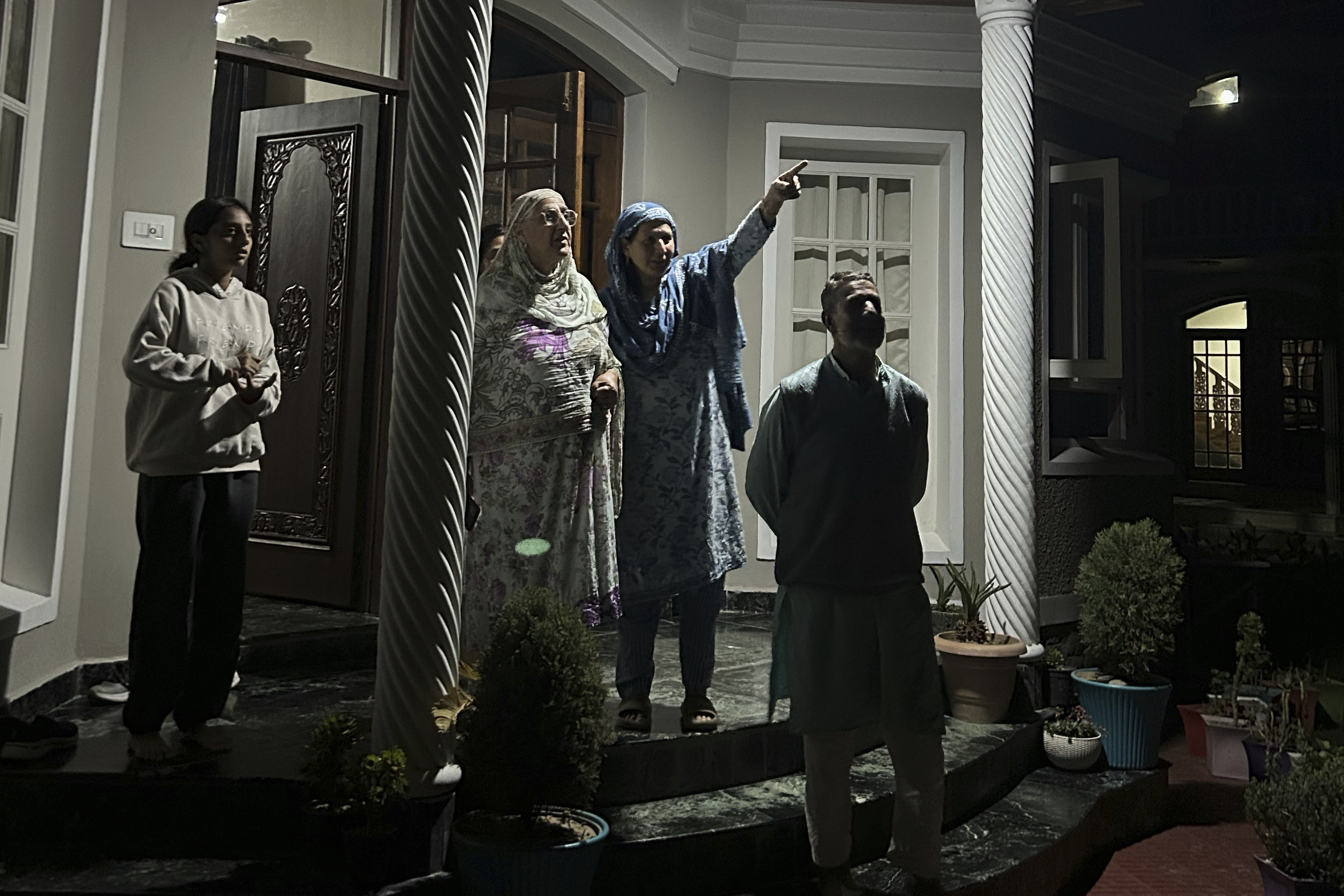 A Kashmiri family watches towards the sky as projectiles fly over the sky in Indian controlled Kashmir, Saturday, May 10, 2025. (AP Photo/Rafiq Maqbool)