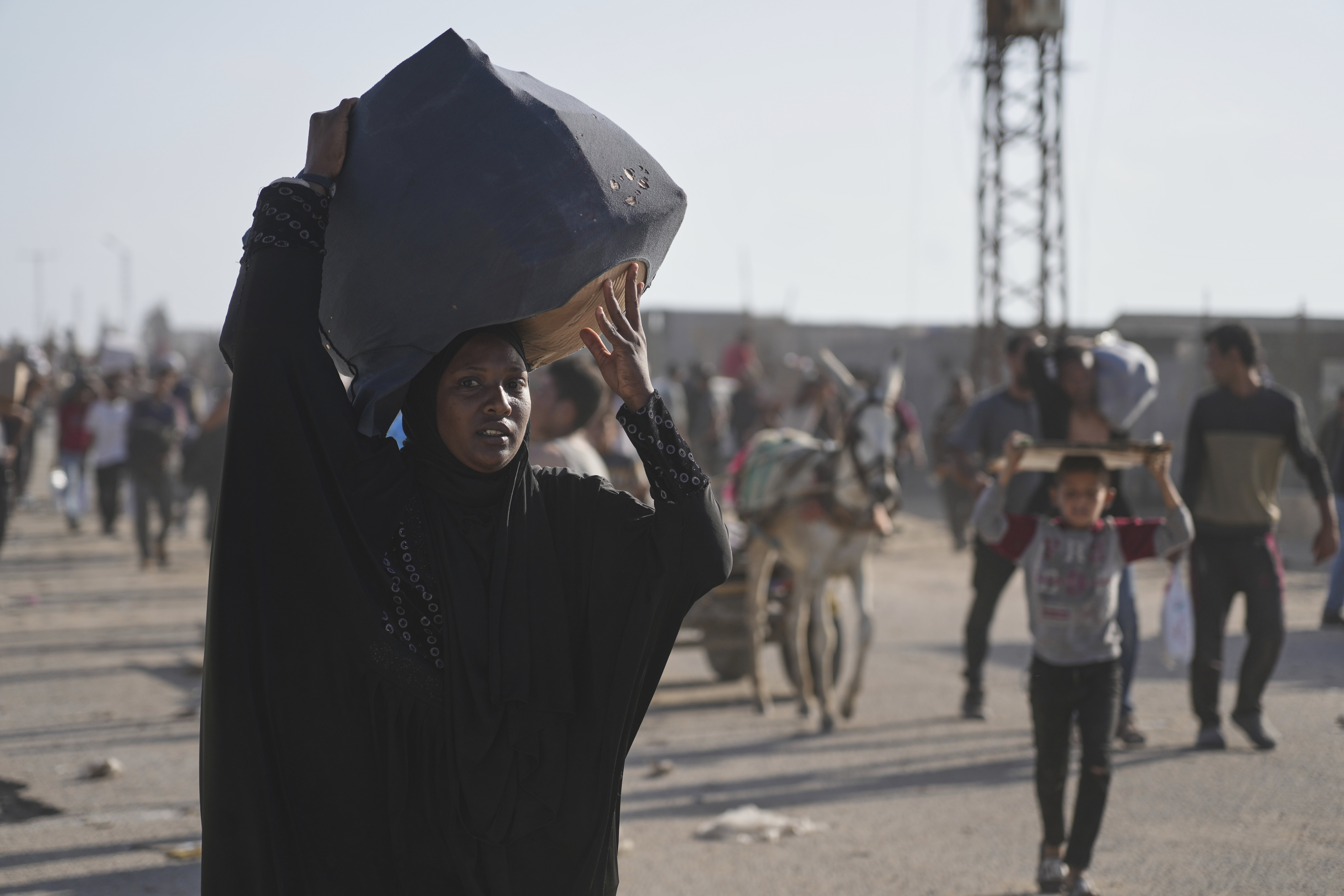 A woman balances a package of food atop her head as she leaves a humanitarian aid centre