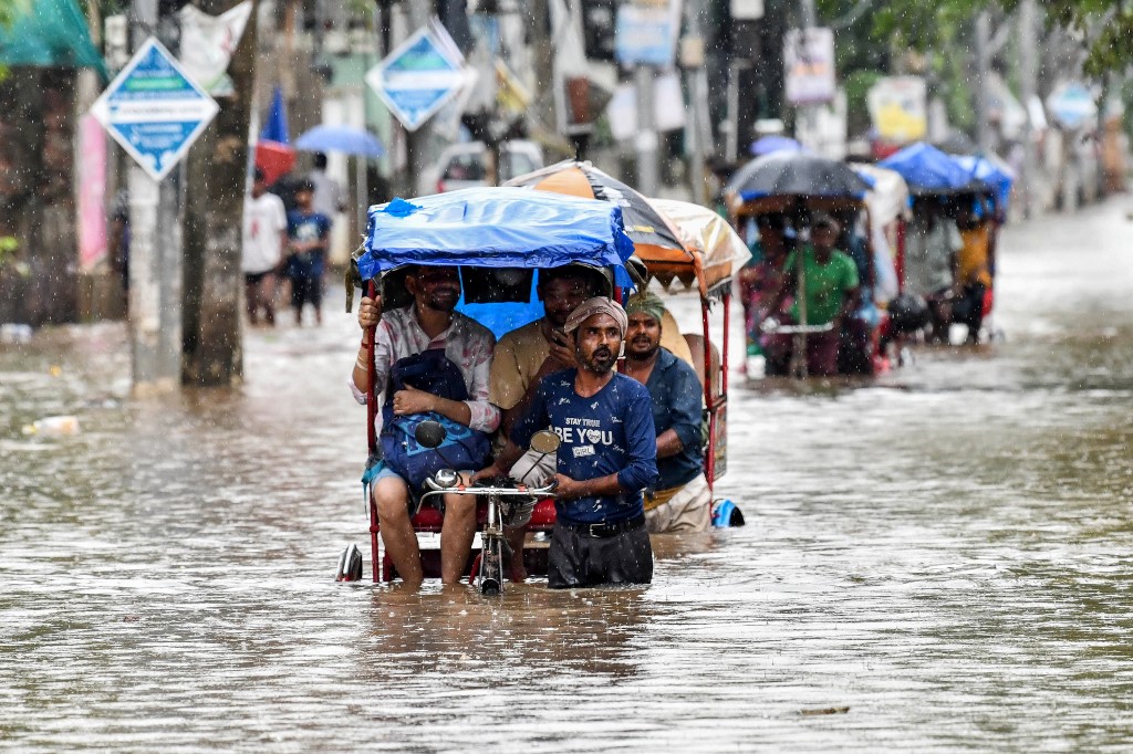 Residents commute in cycle rickshaws through a flooded street after heavy rains in Guwahati, in India's Assam state