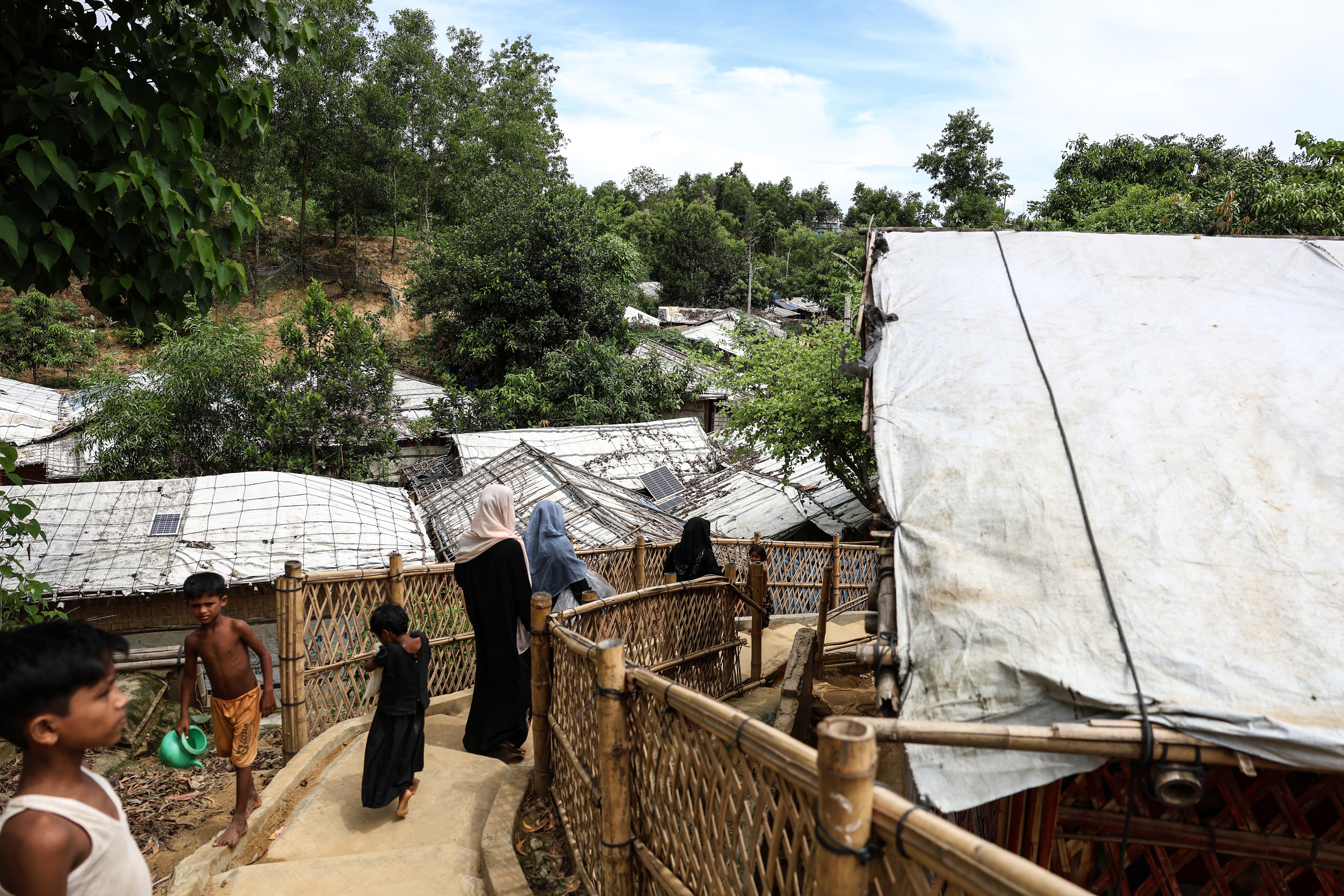 Women and children walk down the street of a Rohingya refugee camp.
