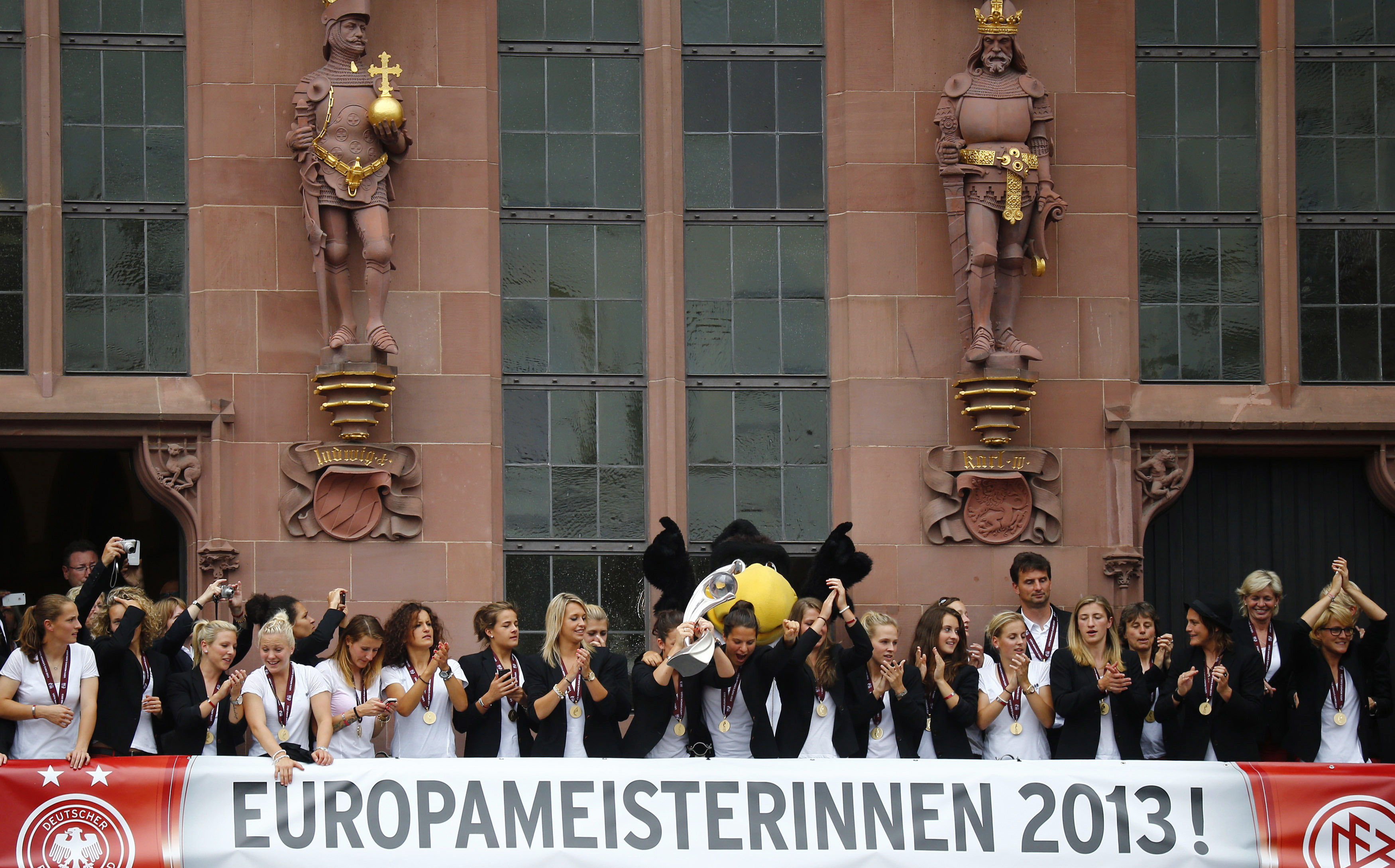 Players of Germany's women's national soccer team present the European Championship trophy during a reception on the balcony of the town hall in Frankfurt, July 29, 2013. Germany defeated Norway 1-0 in the European women's soccer championship with goalkeeper Nadine Angerer (3rd R) saving two penalties in the final. REUTERS/Kai Pfaffenbach (GERMANY - Tags: SPORT SOCCER)
