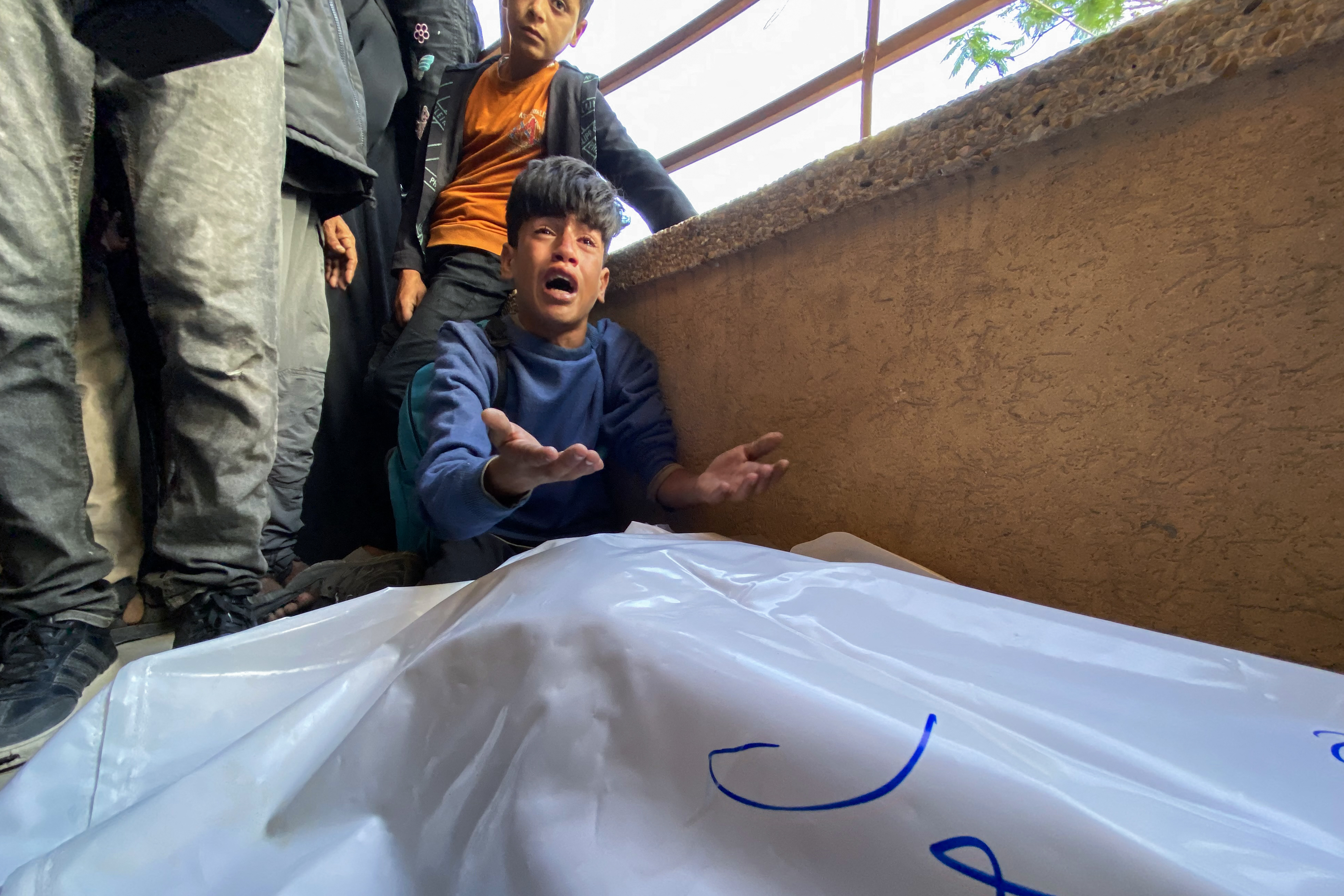 Palestinians mourn by the bodies of relatives killed by Israeli fire near an aid site in Rafah