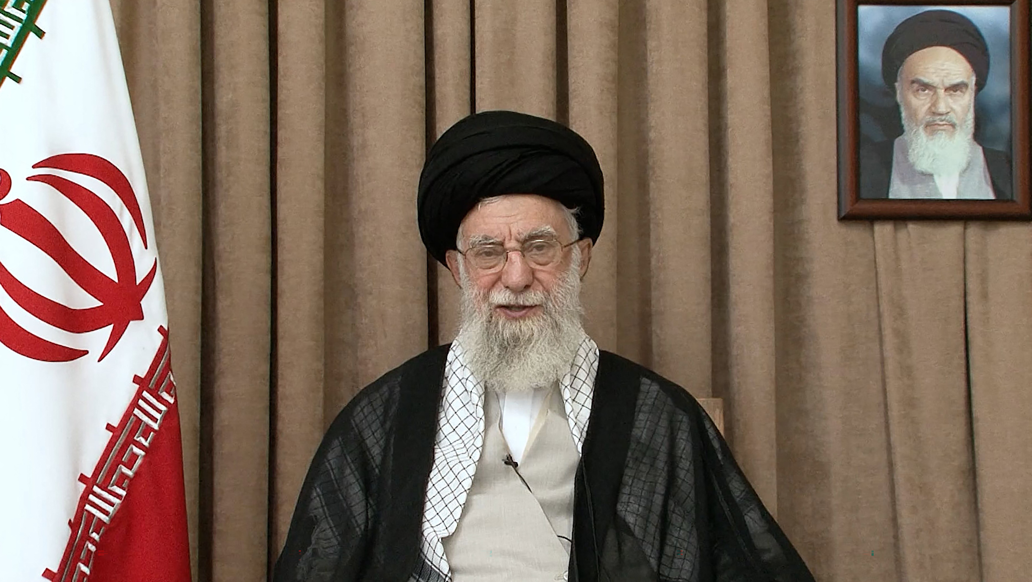 Iran's Supreme Leader Ayatollah Ali Khamenei addresses the nation in front of a portrait of his predecessor, the late founder of the Islamic republic Ayatollah Ruhollah Khomeini, on June 26, 2025.