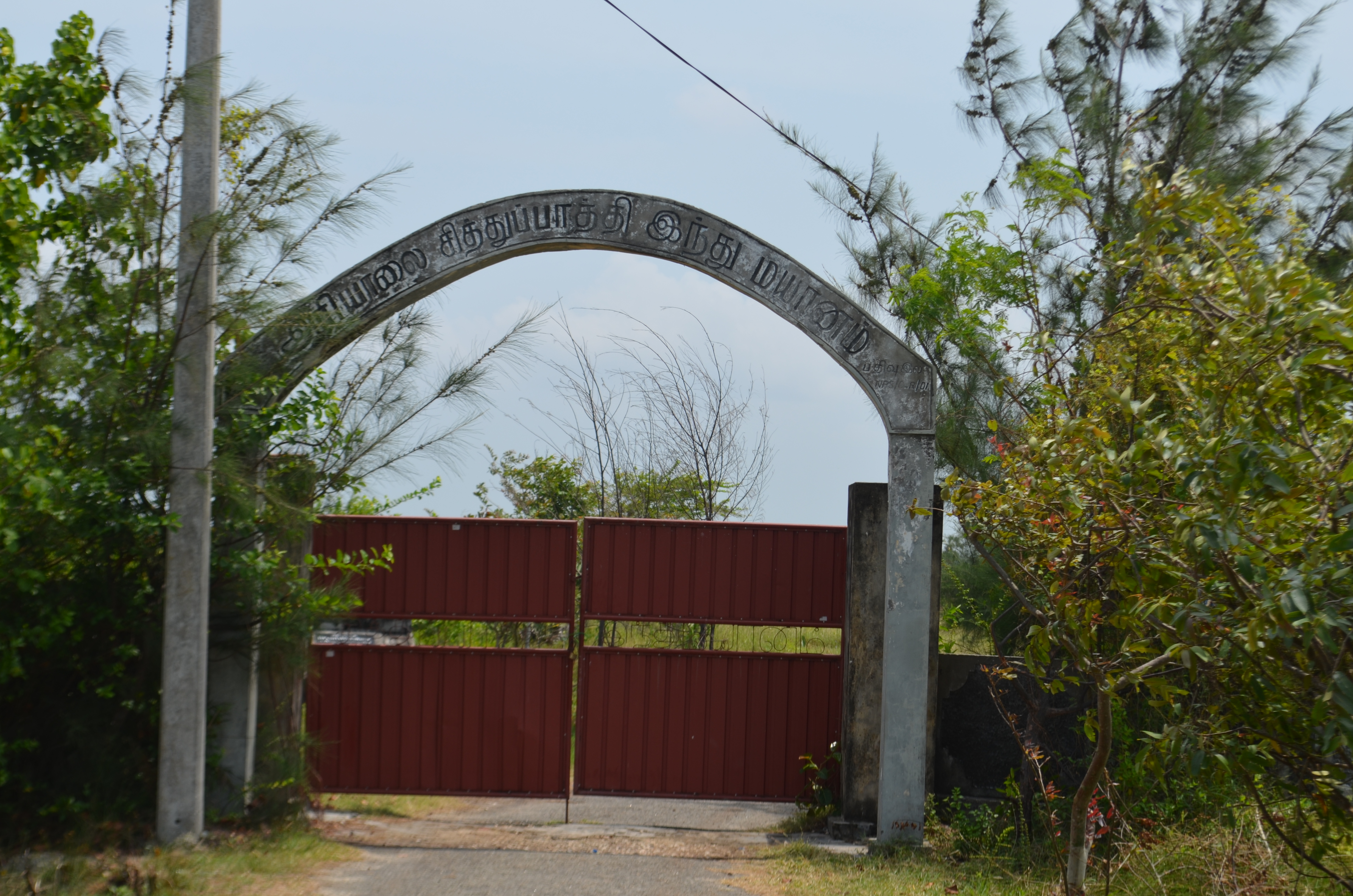 A rusted gate behind which Sri Lankan excavators are digging the latest mass grave they have found from the country's 26-year-long civil war, in Chemmani, Sri Lanka [Jeevan Ravindran/Al Jazeera]