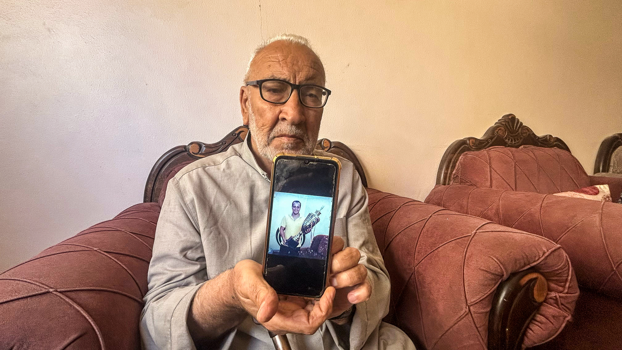 Safi's father showing images of his deceased son.