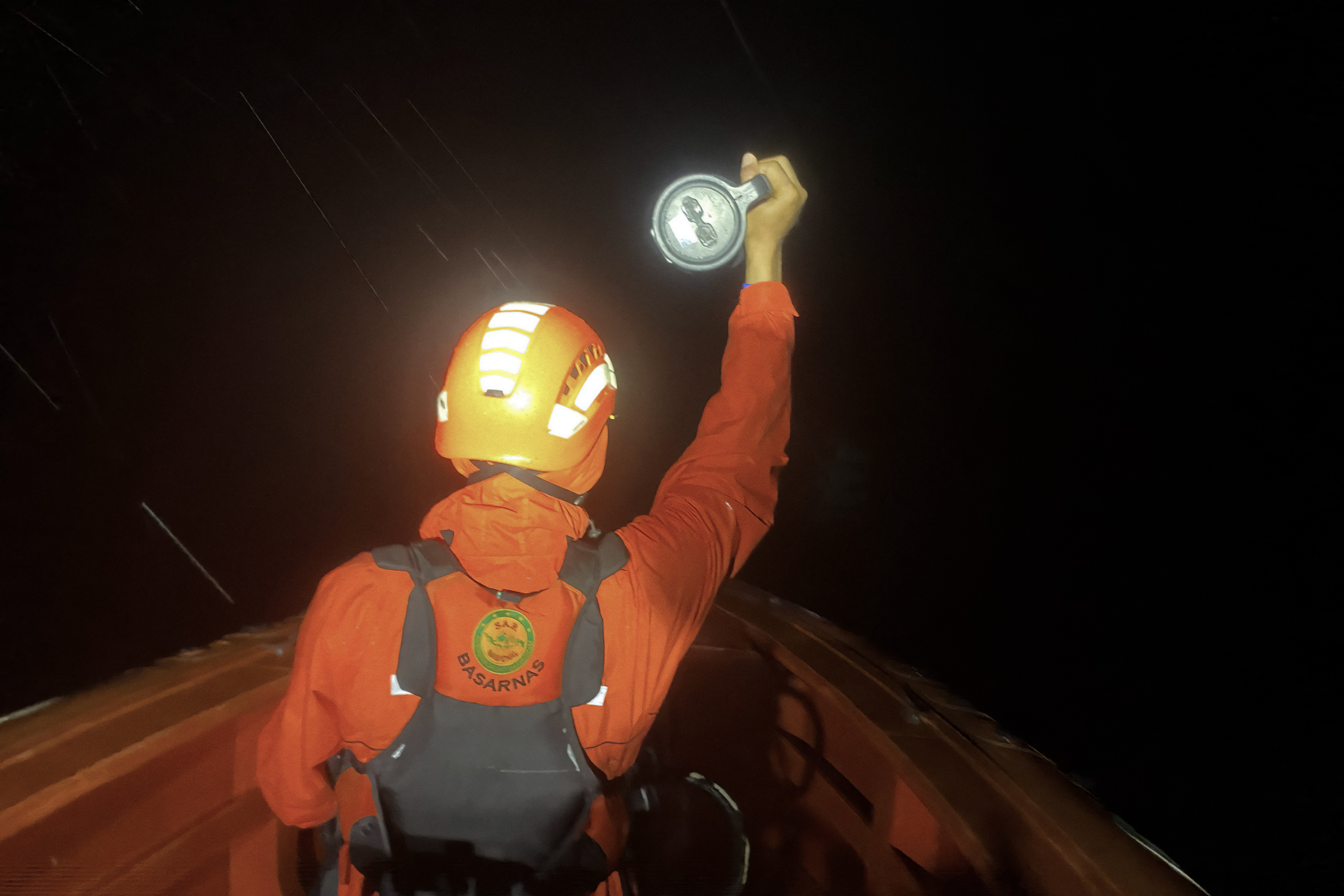 This handout photo taken and released on July 15, 2025 by Indonesia's National Search and Rescue Agency shows a responder using a flashlight during the search for victims of a capsized boat in the waters off Mentawai Islands, West Sumatra.