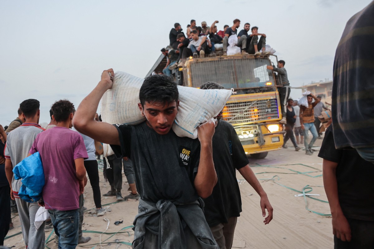 Palestinians carry aid parcels brought into northern Gaza through the Zikim border crossing in July