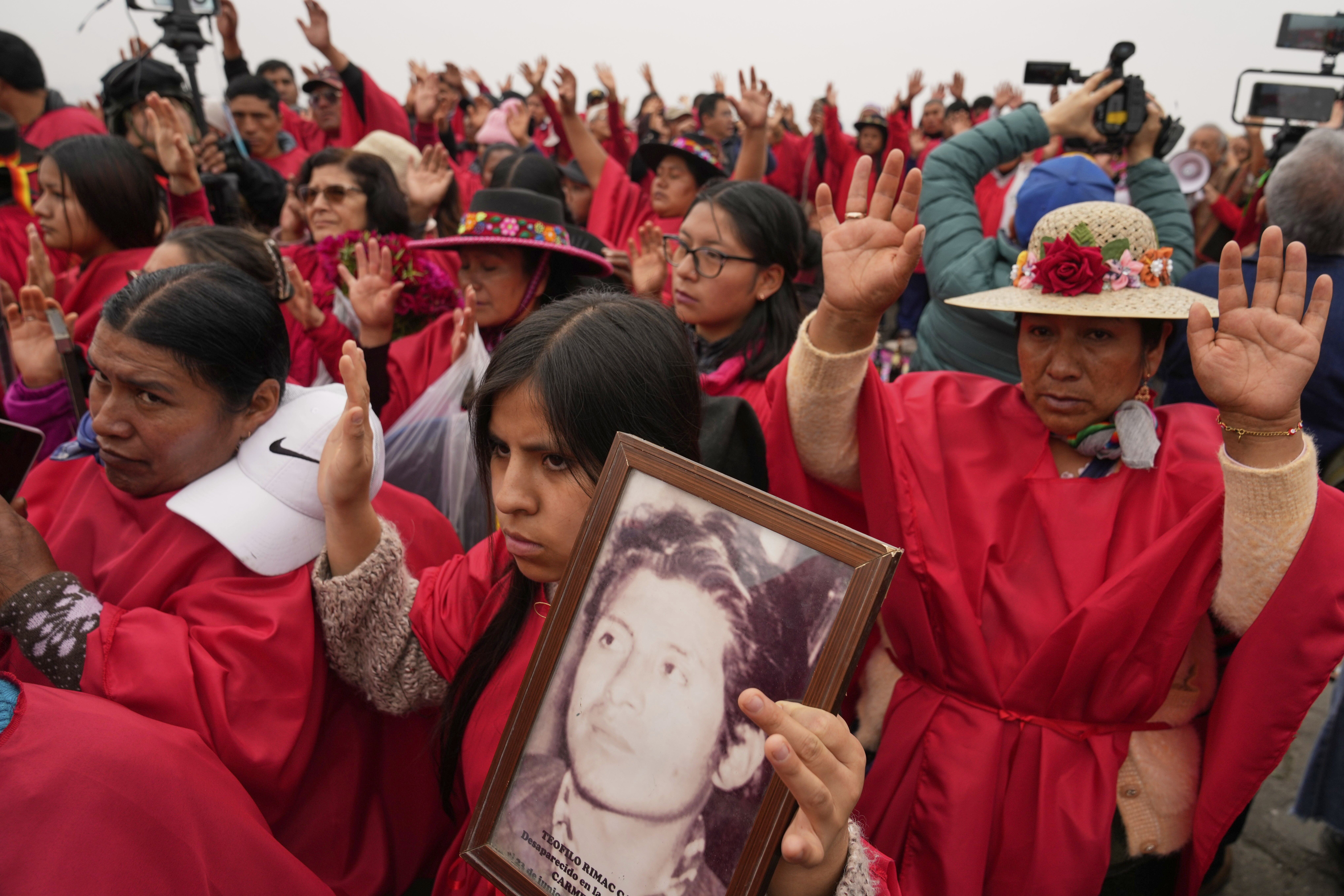 Peruvian protesters wearing traditional attire hold up portraits of people killed during the internal conflict from 1985 to 2000.
