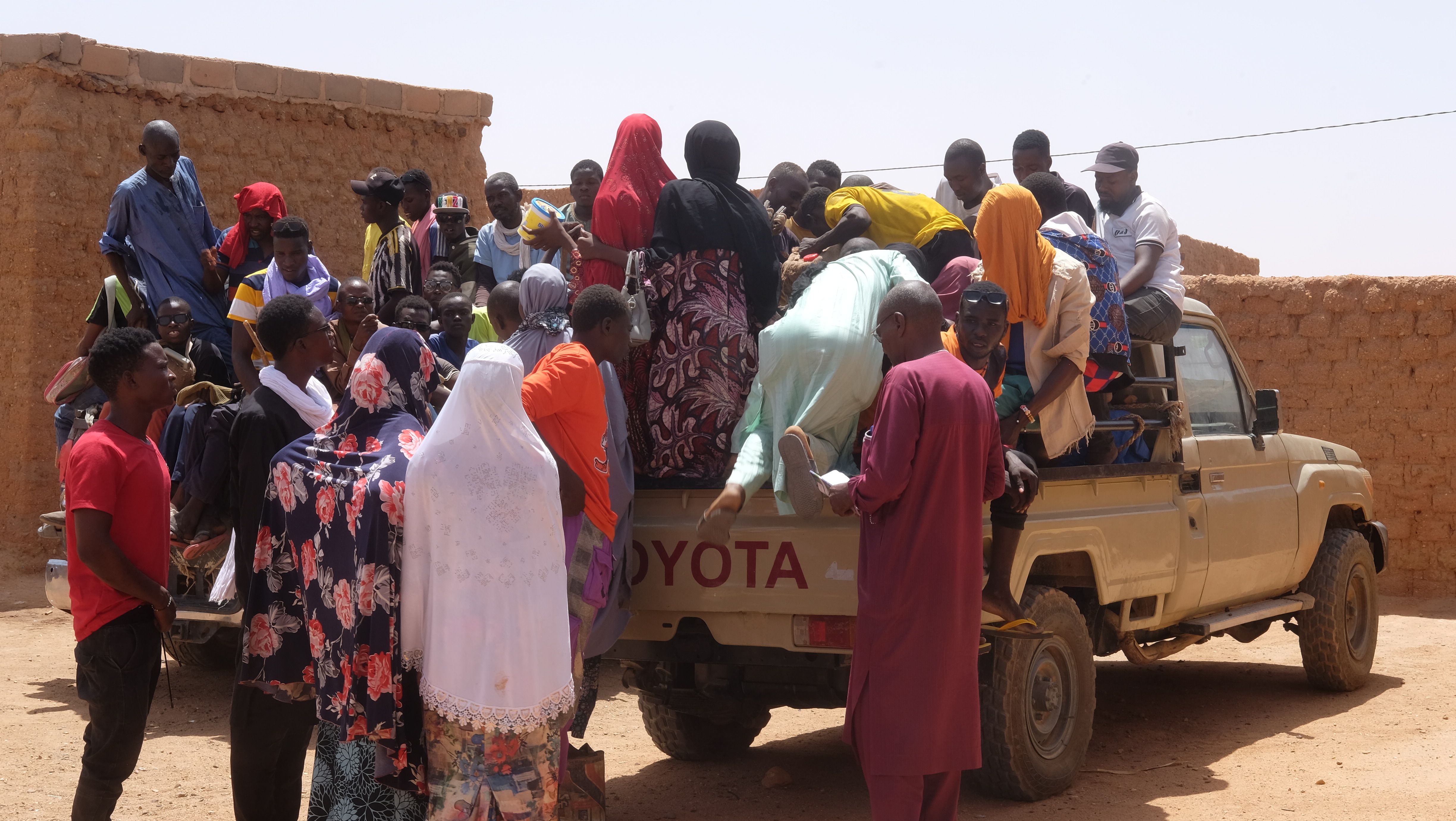 Migrant travellers get into the back of a pickup truck, preparing to head out to the desert