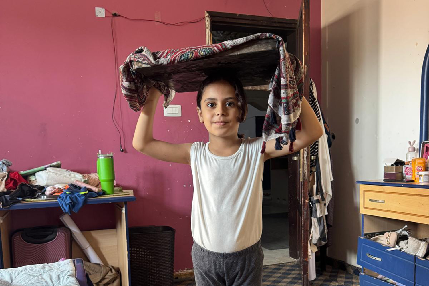 A little girl, Banias, holding the tray with her family's meager supply of food for the day on her head