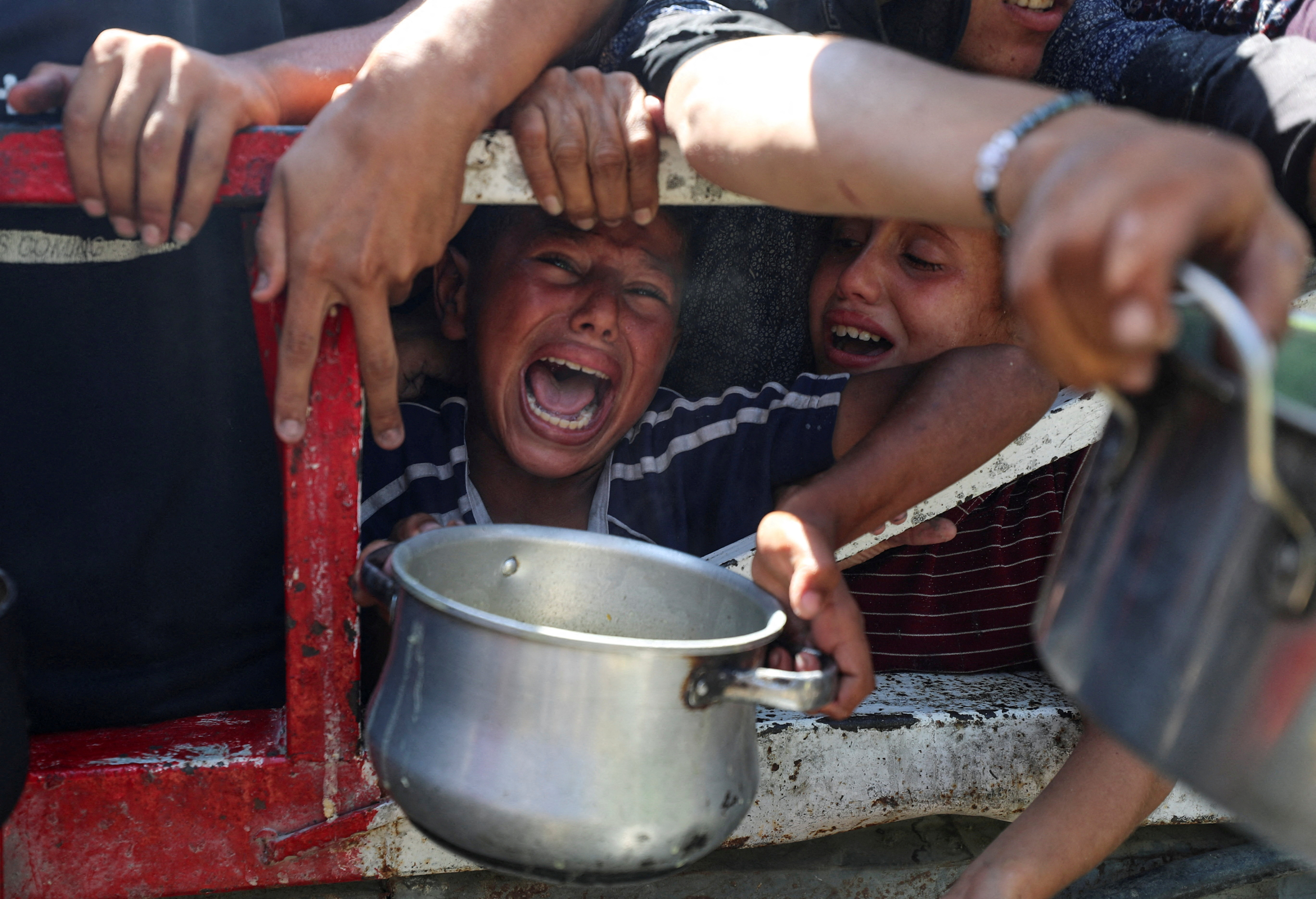 Palestinians wait to receive food from a charity kitchen, amid a hunger crisis, in Gaza City, July 23, 2025. REUTERS/Mahmoud Issa TPX IMAGES OF THE DAY